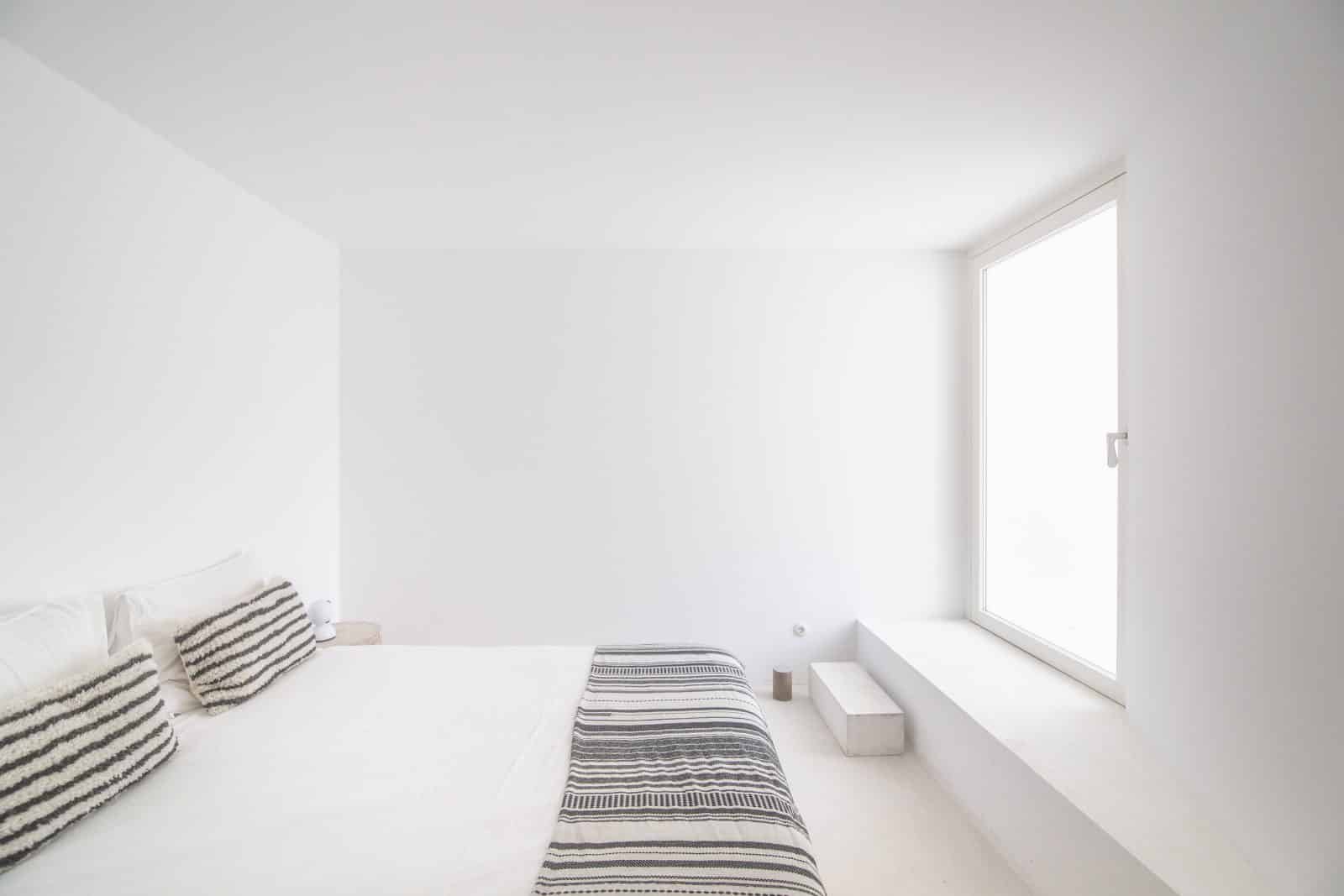 Minimalistisches Schlafzimmer in weiß mit großem Fenster