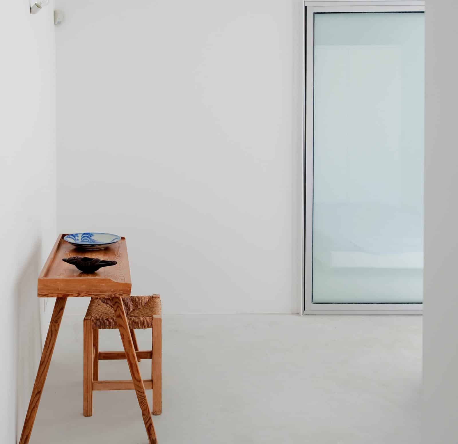 Minimalistischer weißer Raum mit kleinem HolzTisch und -Stuhl