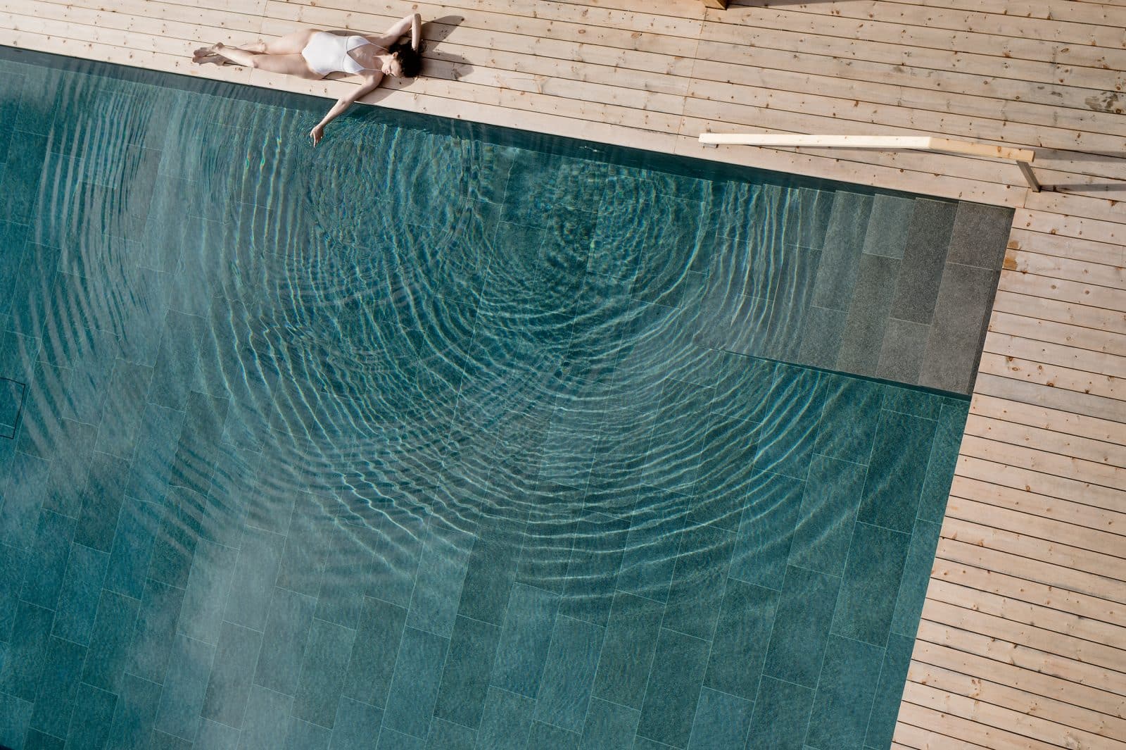 Gast liegt mit ausgestreckten Armen am Rand des Pools im Hotel Schwarzwscmied