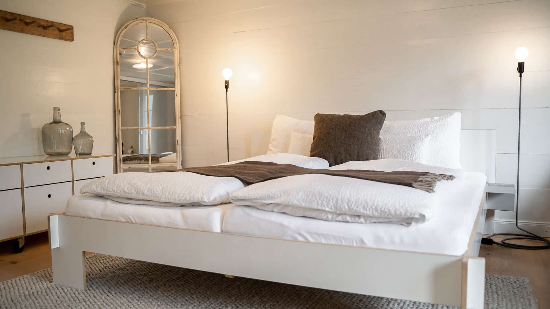 Bett, Kommode und Spiegel im Hotelzimmer der Lenk Lodge
