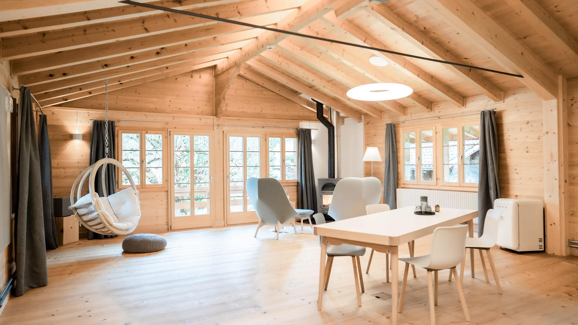 Großes Wohnzimmer mit Esstisch und Kamin in der Lenk Lodge