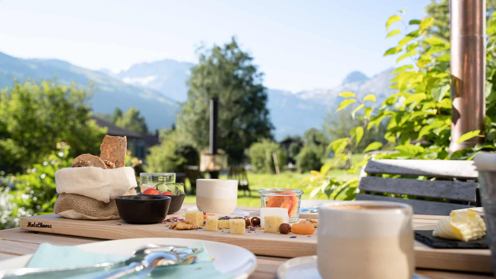 Frühstücksplatte mit Brot und Käse im Garten der Lenk Lodge