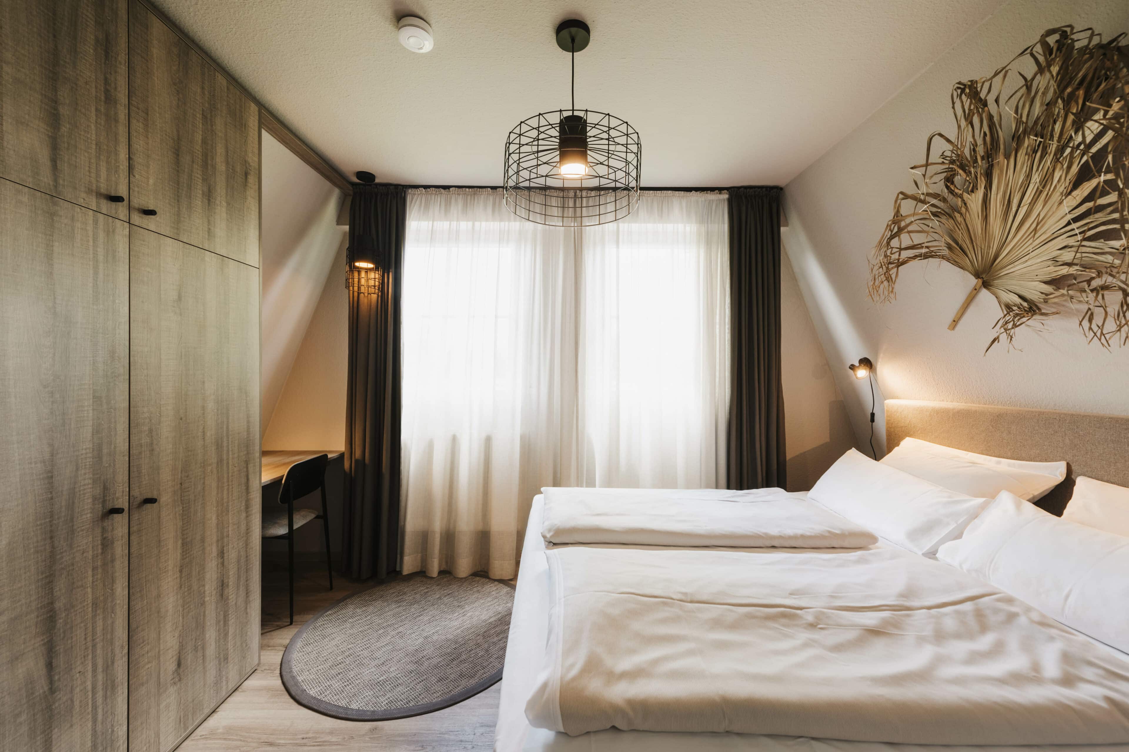 Doppelbett und Palmblatt als Wanddeko und Schrank im Seehotel Gronau