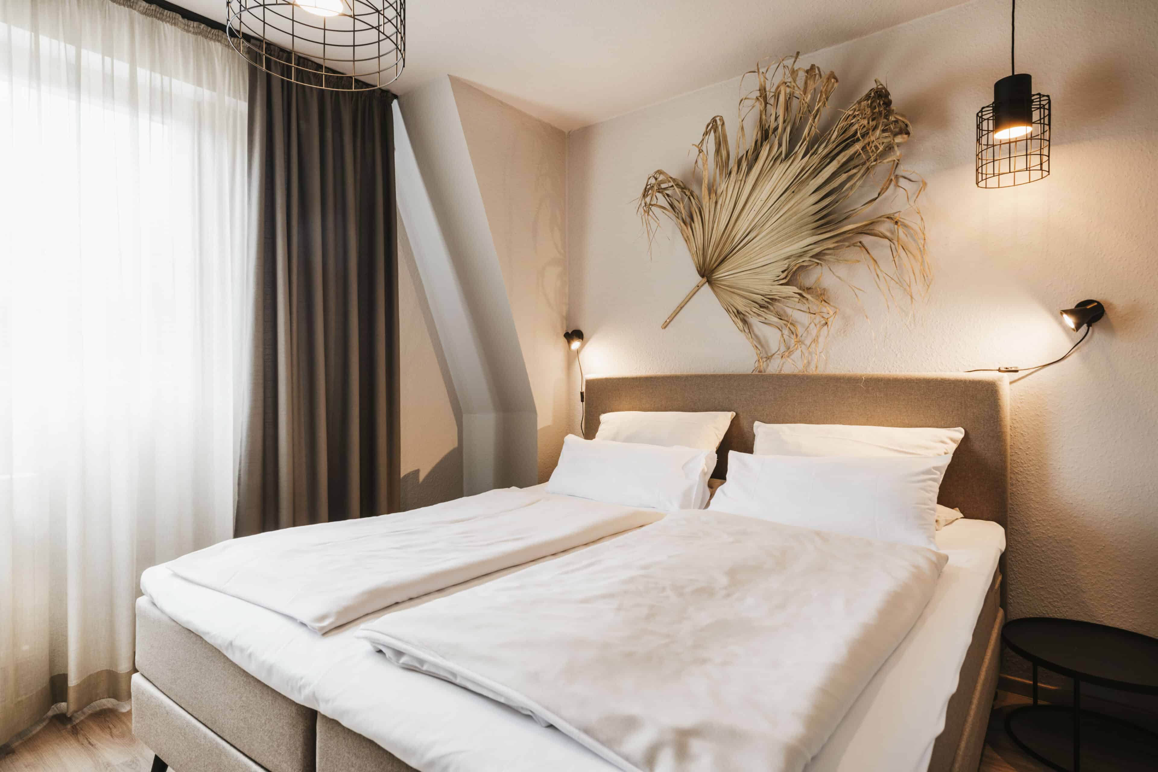 Doppelbett und Palmblatt als Wanddeko im Seehotel Gronau