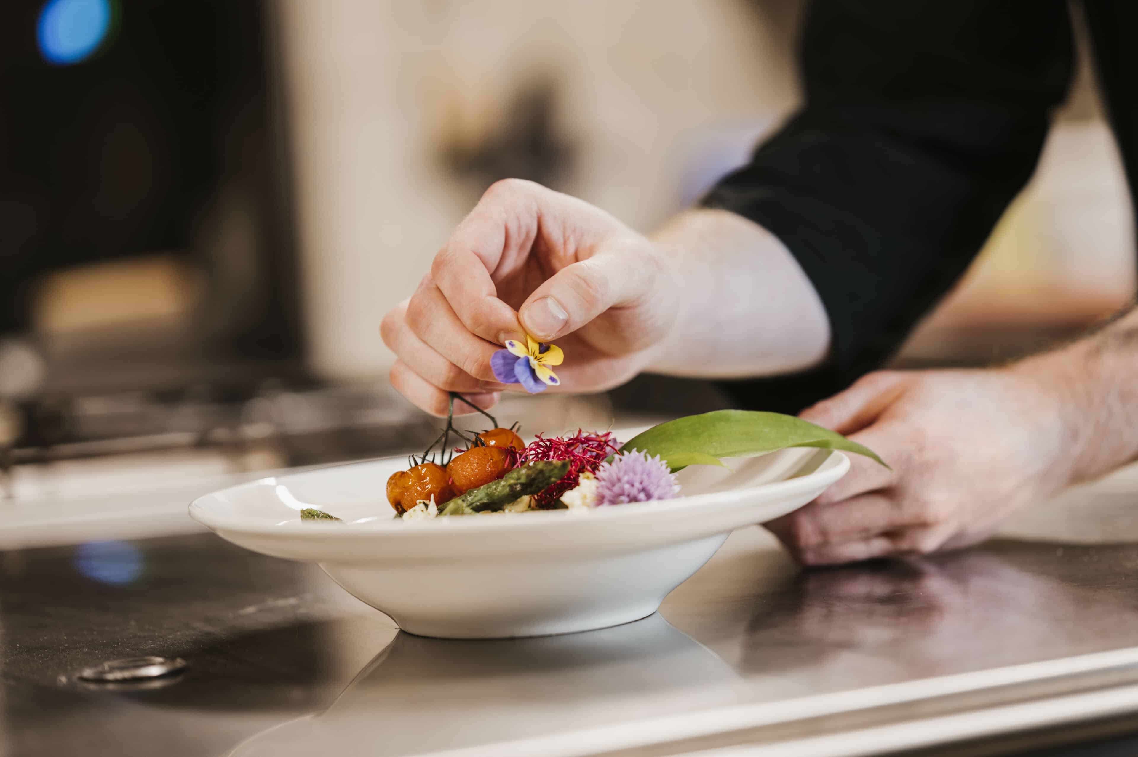 Hand, die eine Schüssel mit einer Blüte dekoriert im Seehotel Gronau