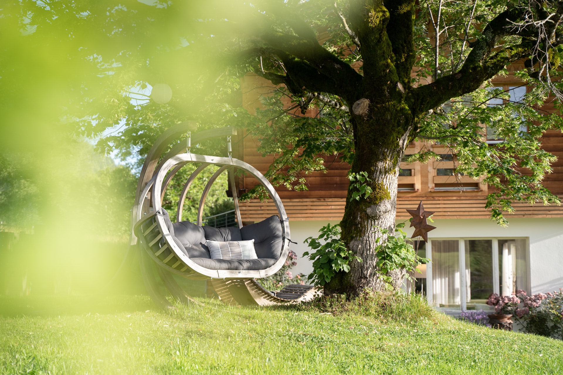 Zweipersonen-Hängesessel am Baum im Garten der Lenk Lodge