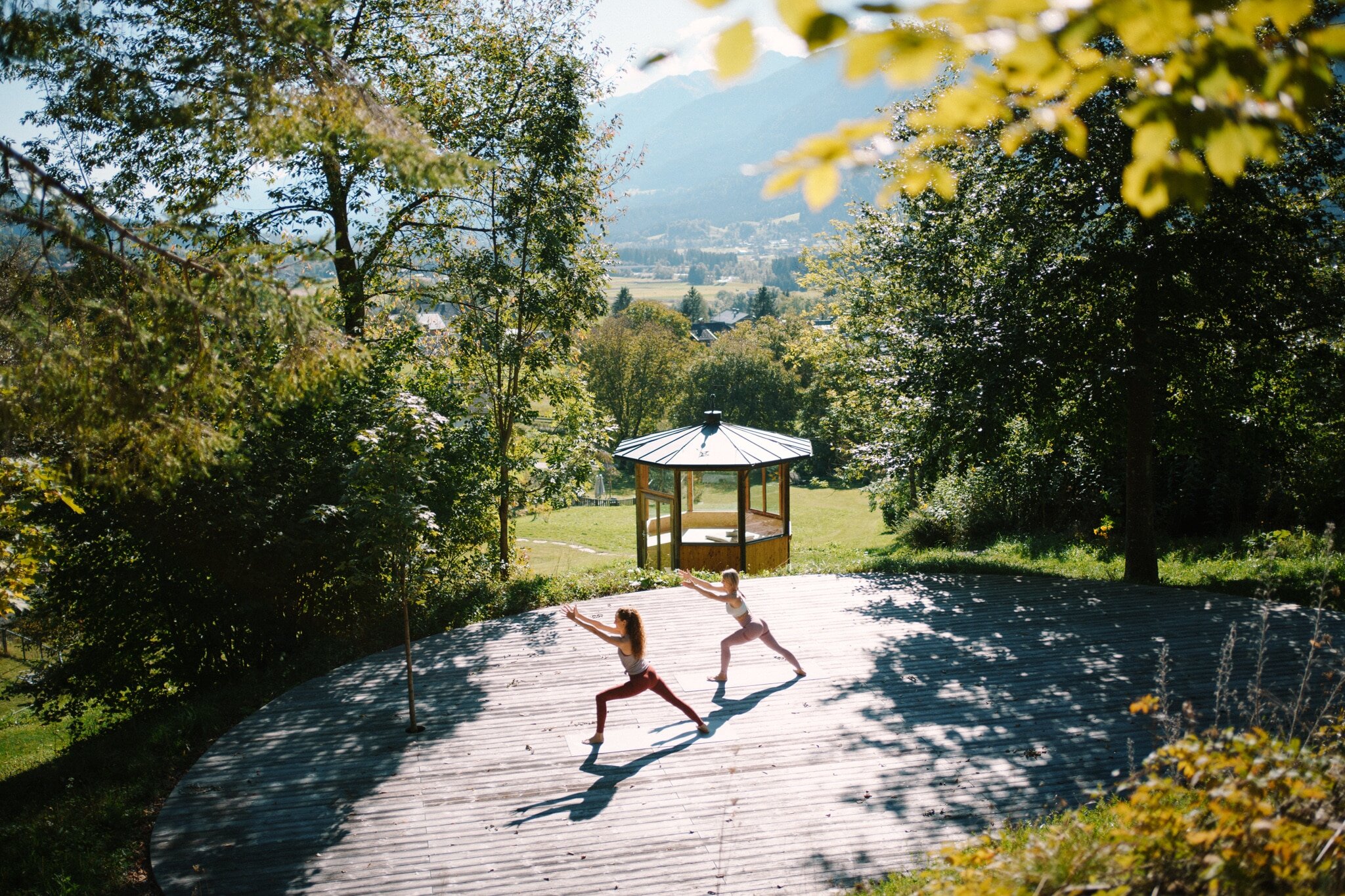 2 Personen die auf einem runden Terrassendeck Yoga machen