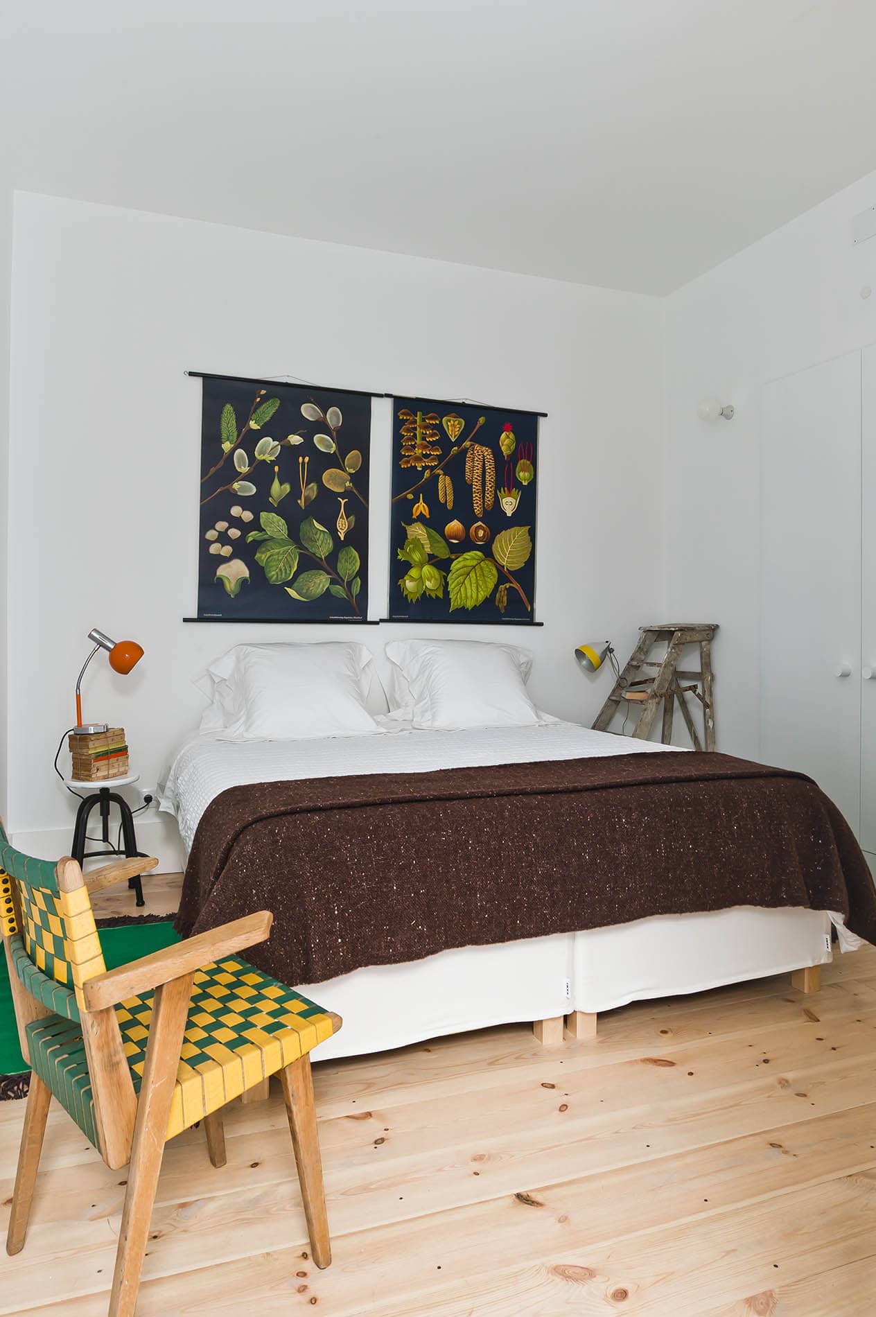Doppelbett mit Pflanzenplakat und Stuhl im Baixa House