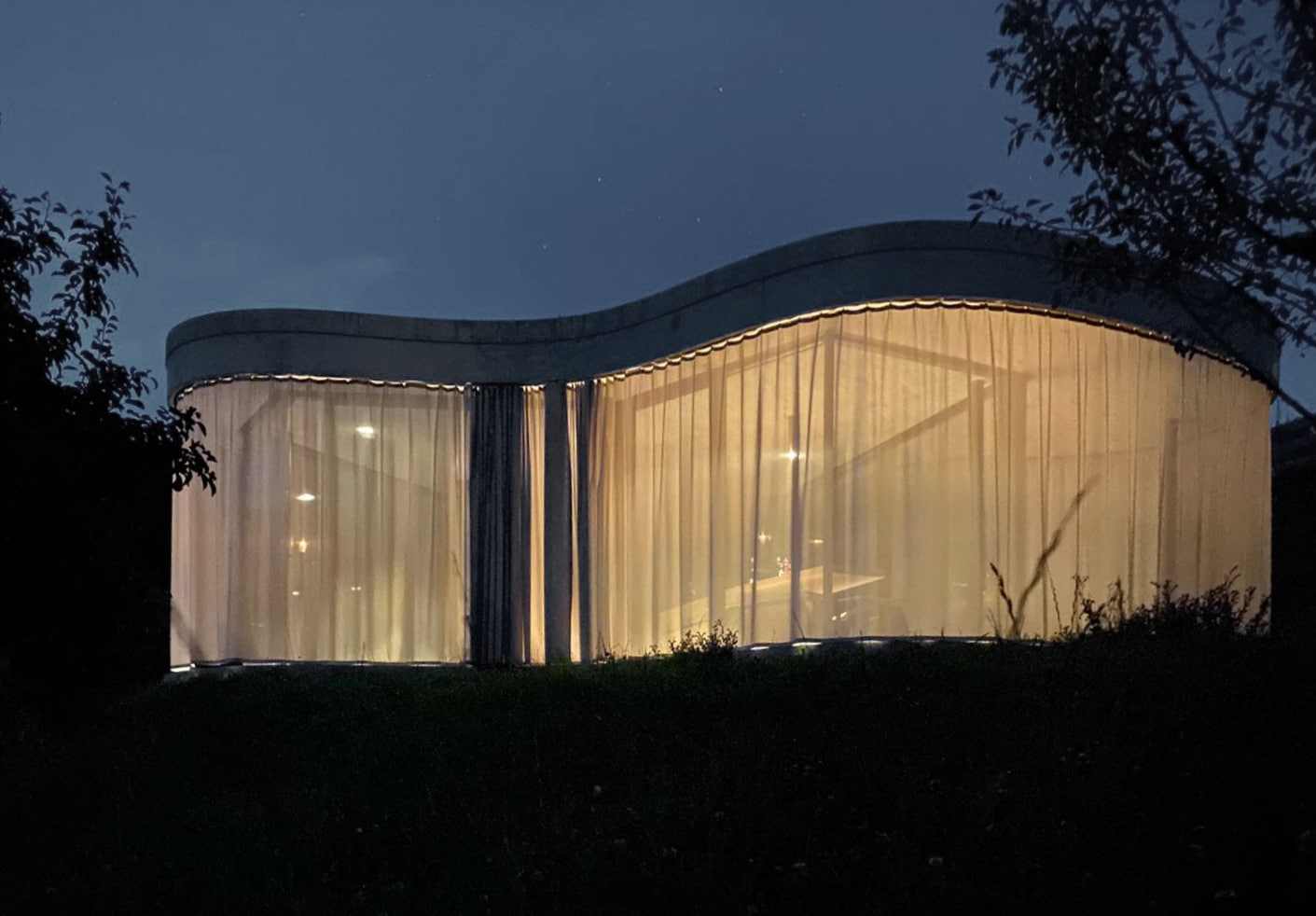 zugezogene Gardine und beleuchtete Räume des Gästehaus Freiform