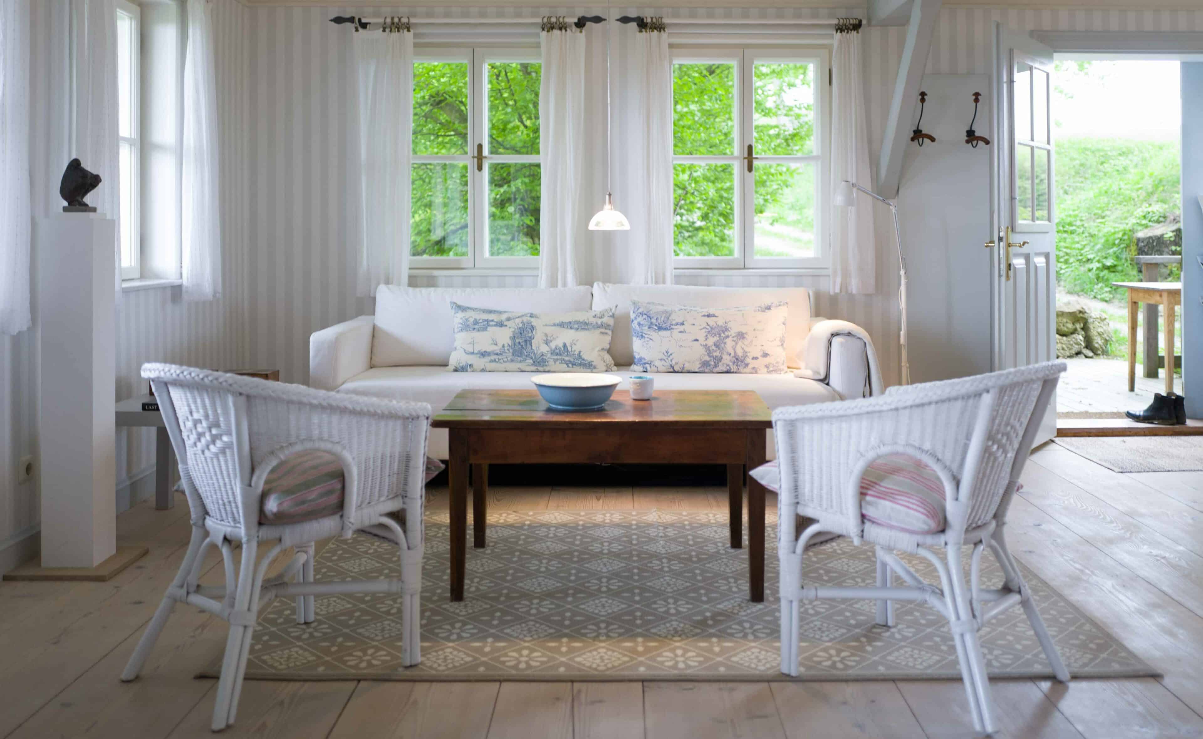 Wohnraum mit Sofa und Korbstühlen und Tür zum Garten auf Hof Grillenöd