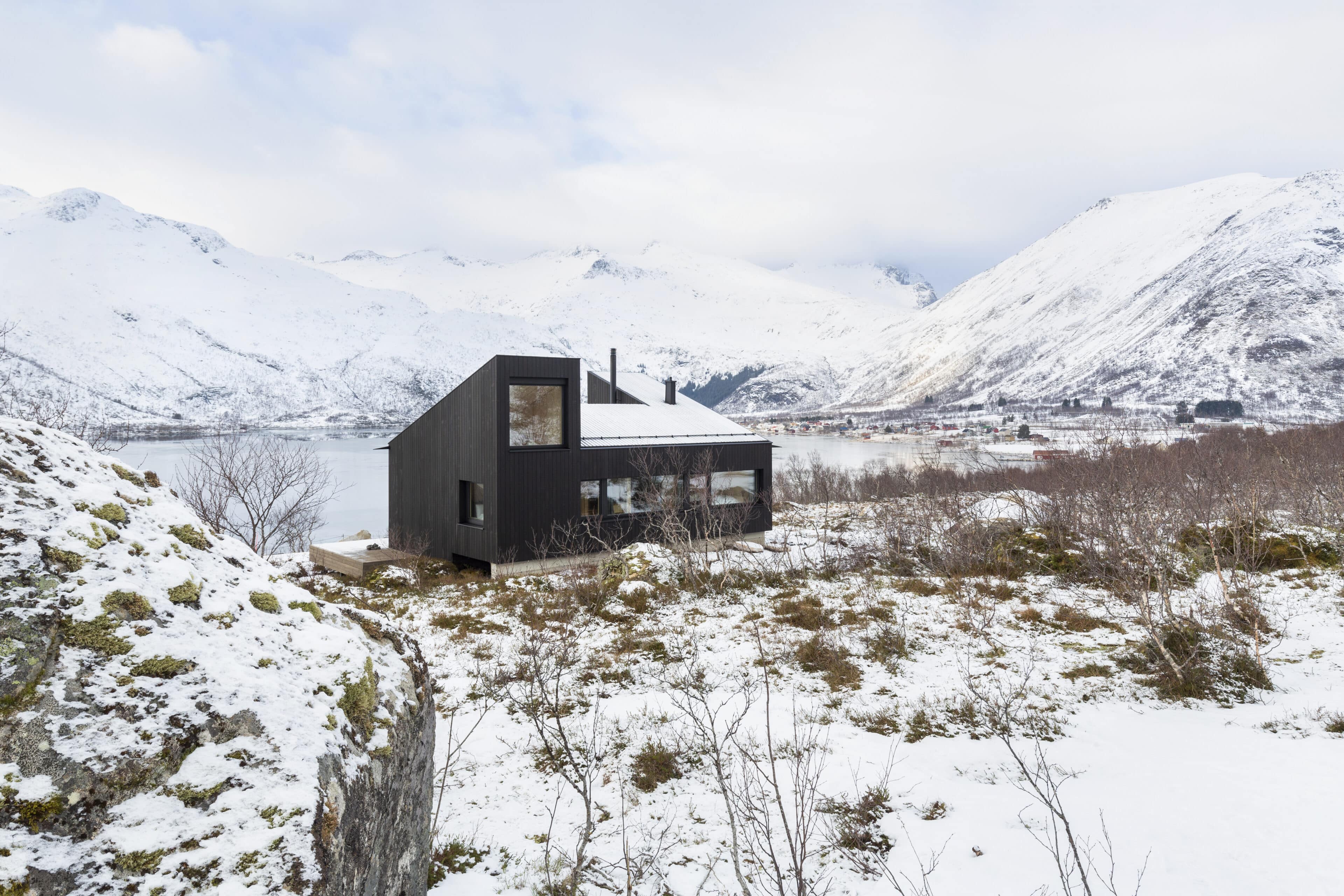 Holzkubus vor schneebedeckten Bergen
