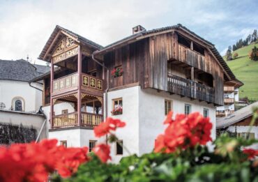 Blick auf die Ferienunterkunft Ciasa Somür mit Blumen im Vordergrund