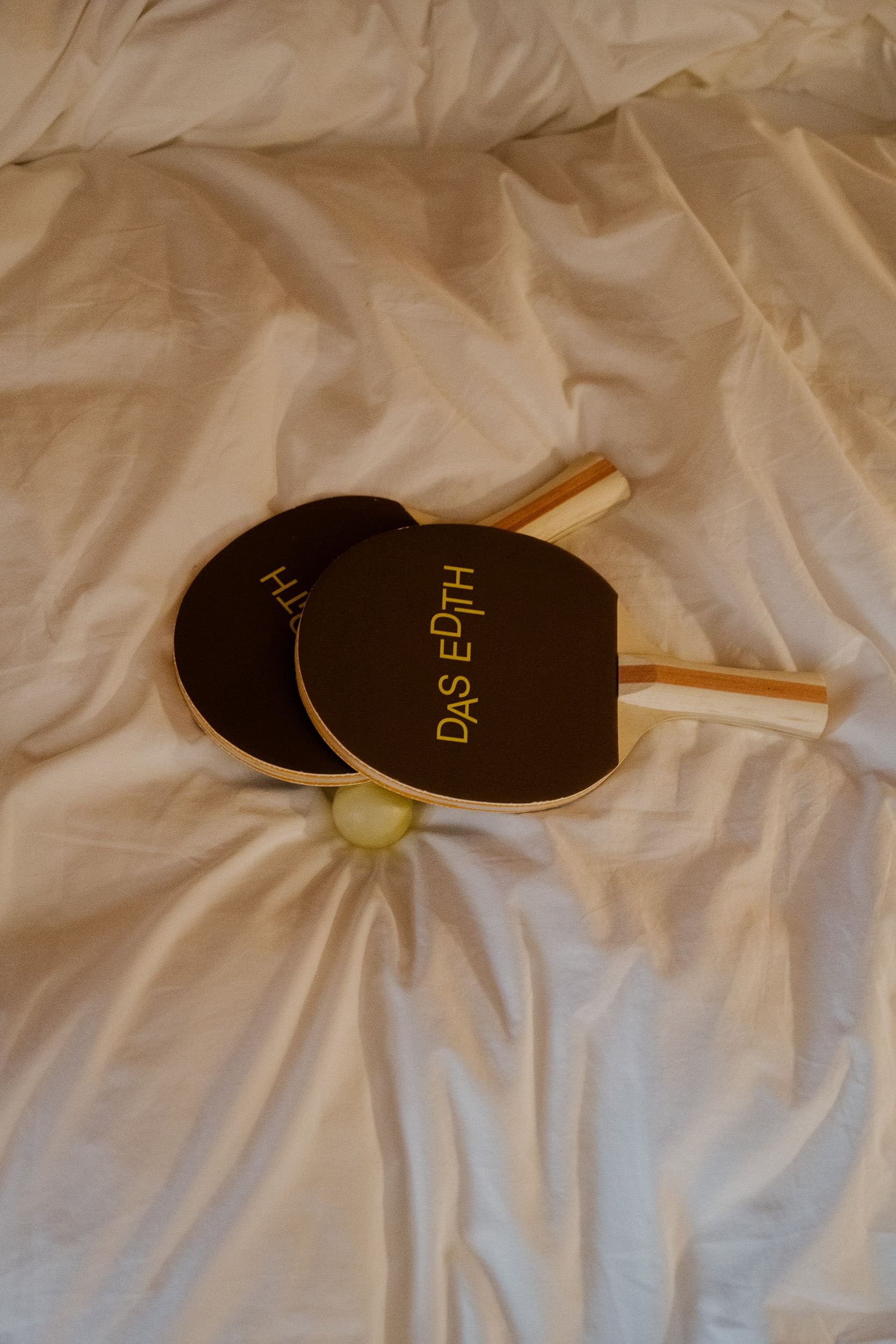 Tischtennisschläger und Tischtennisball auf Bettdecke