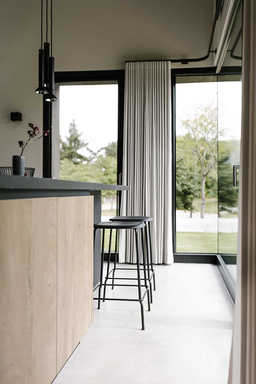 Küchenzeile mit Barhockern und Blick durch bodentiefe Fenster