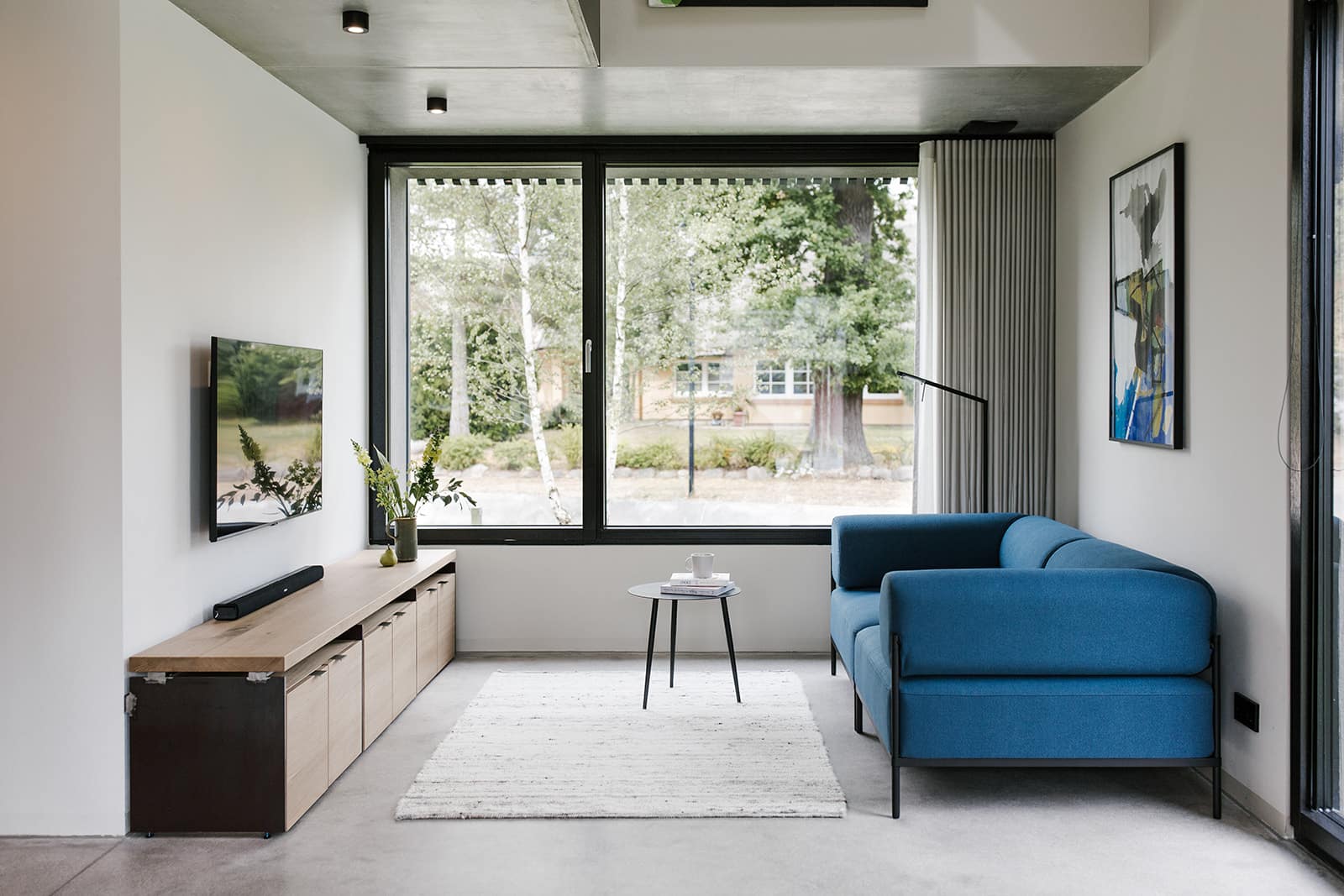 Wohnzimmer mit Couch und großem Fenster mit Blick in den Garten