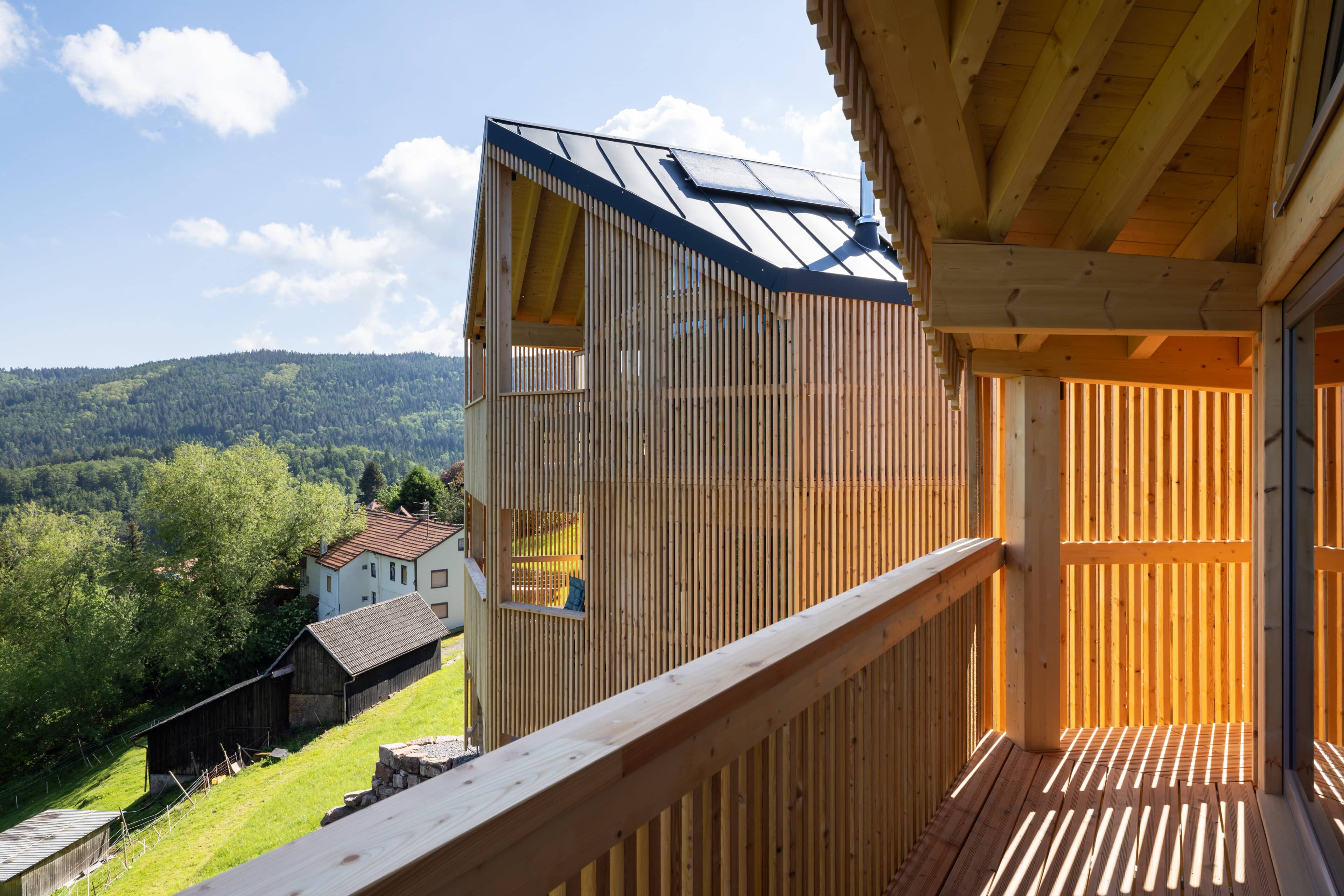 Balkon mit Holzstreben und Blick auf das Nachbarhaus und die Umgebung
