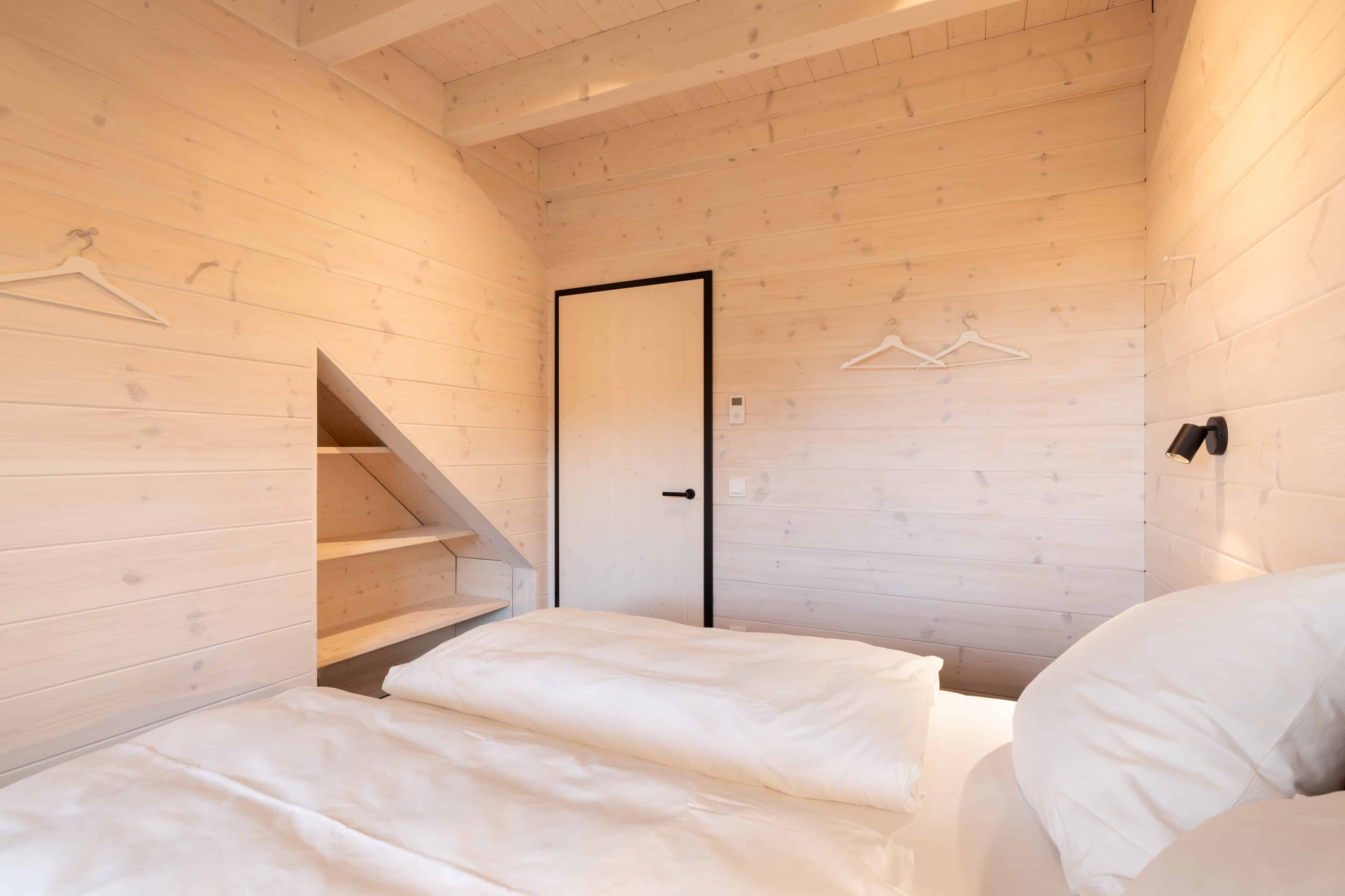 Schlafzimmer mit heller Holzvertäfelung und Einbauregal