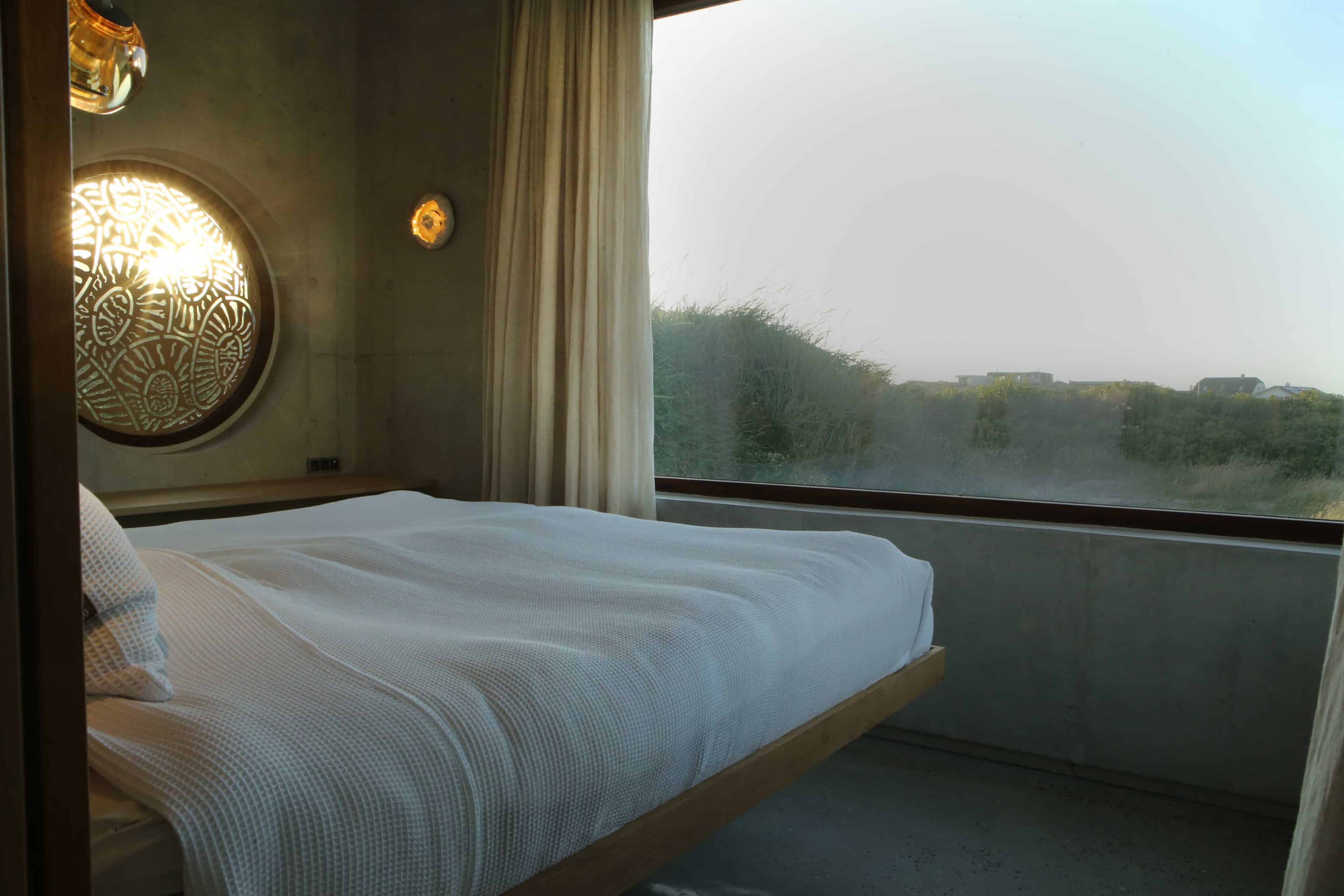 Schlafzimmer mit großem Fenster und Ausblick auf die Dünen