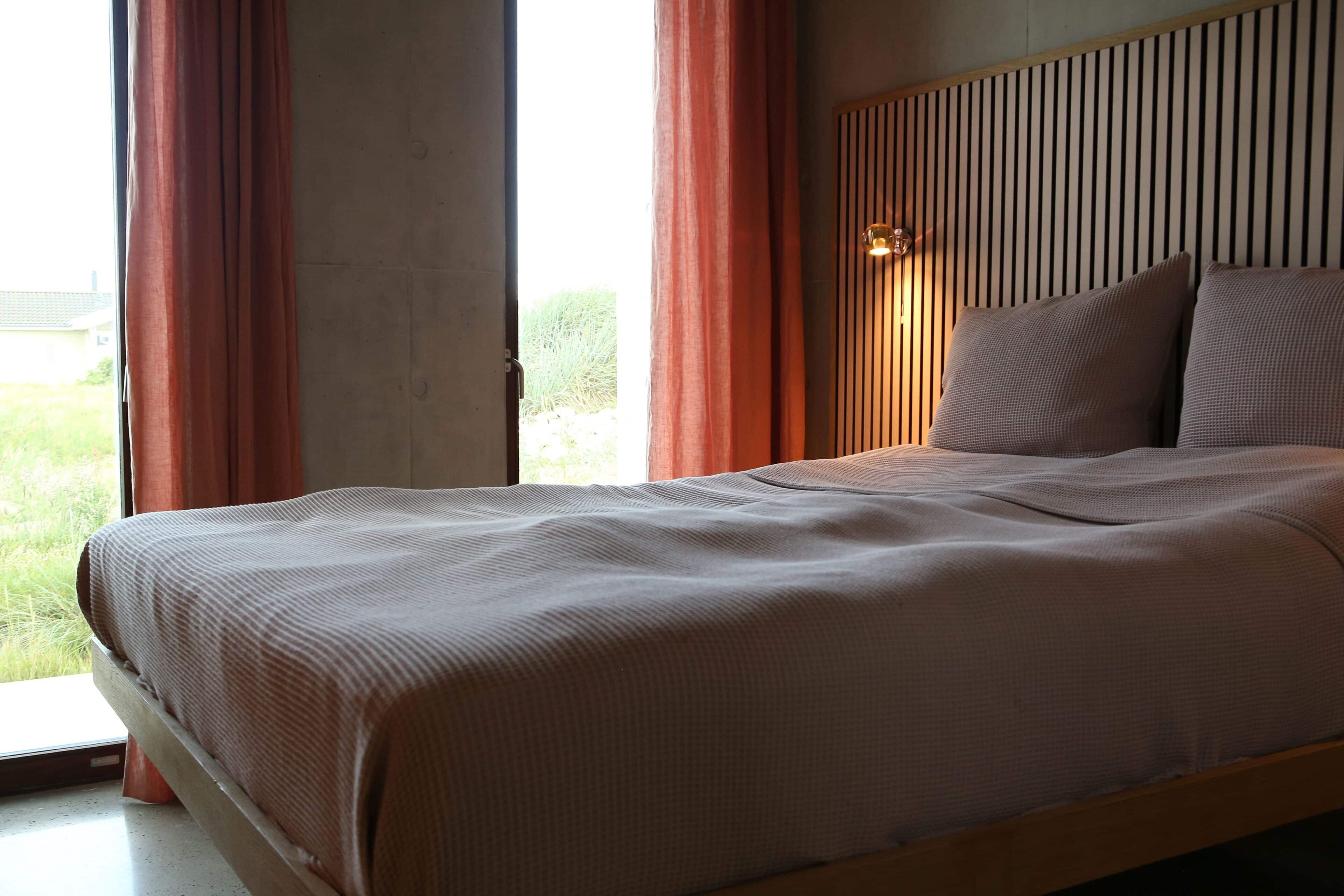 Schlafzimmer mit Doppelbett und bodentiefem Fenster