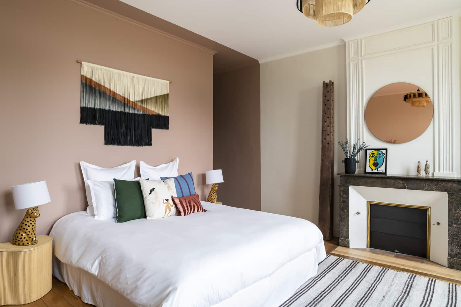 Doppelbett mit bunten Kissen im Schlafzimmer mit Kamin