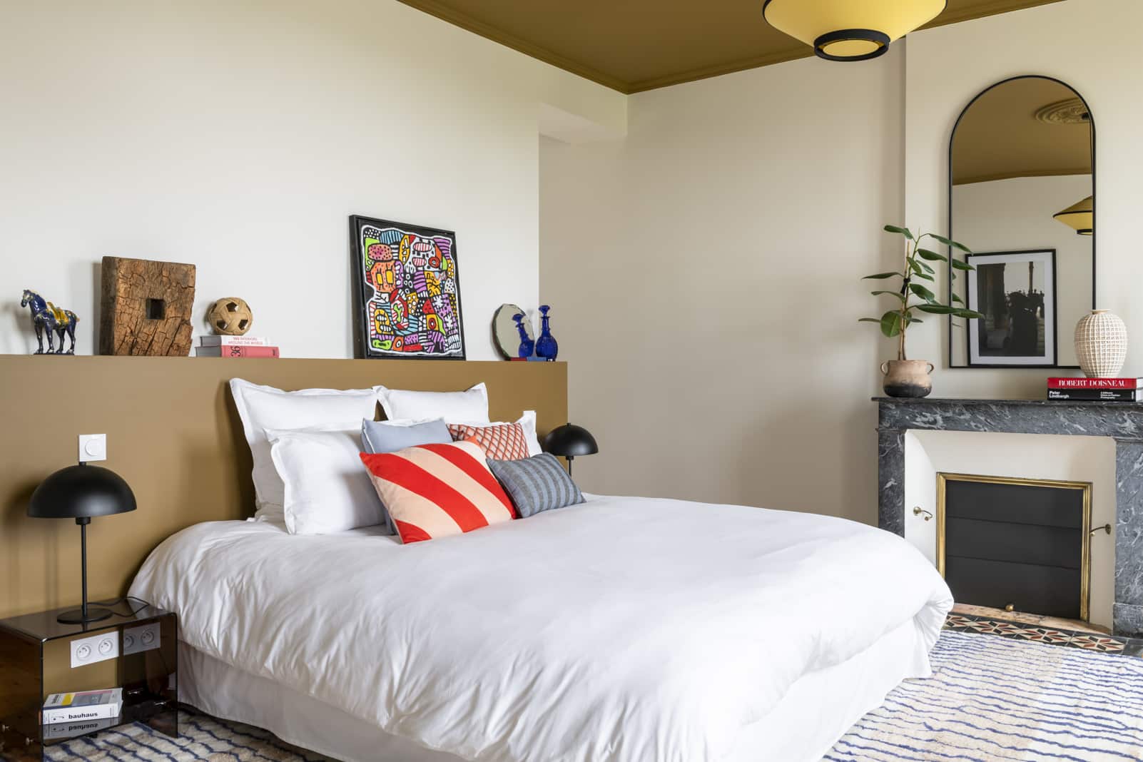 Doppelbett mit bunten Kissen, Bilder auf dem Sims