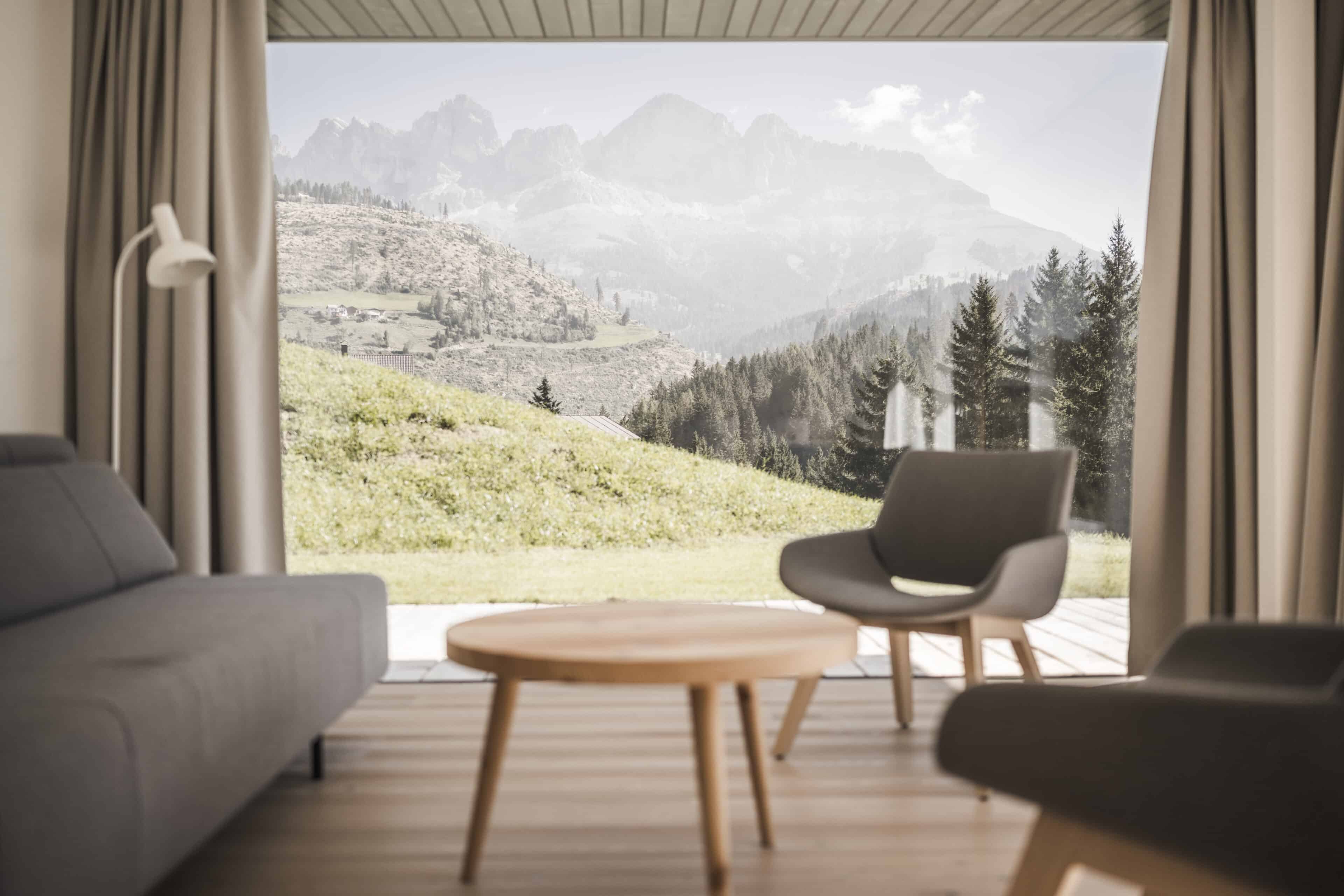 Wohnzimmer mit bodentiefem Fenster und Ausblick in die Berge
