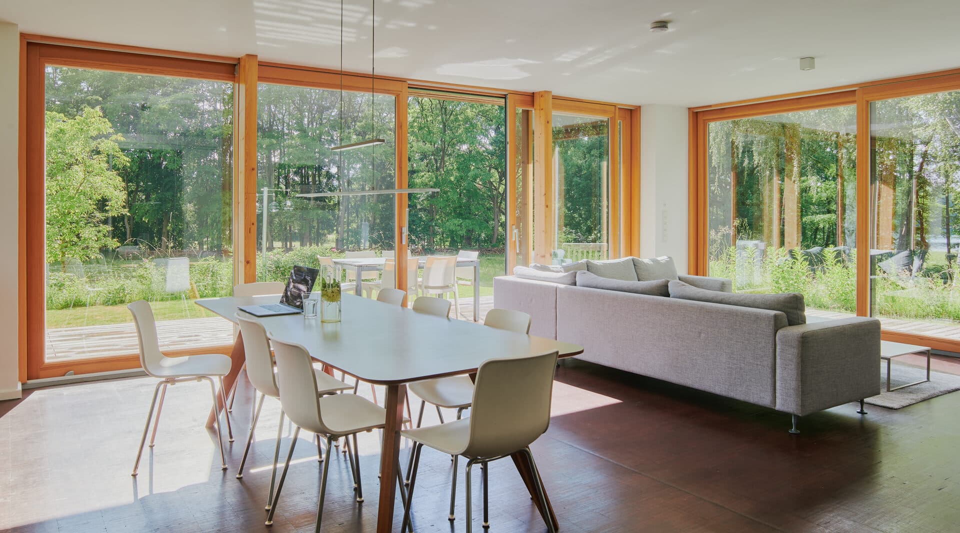 Wohnzimmer mit Esstisch, Sofa und großen Panoramafenstern