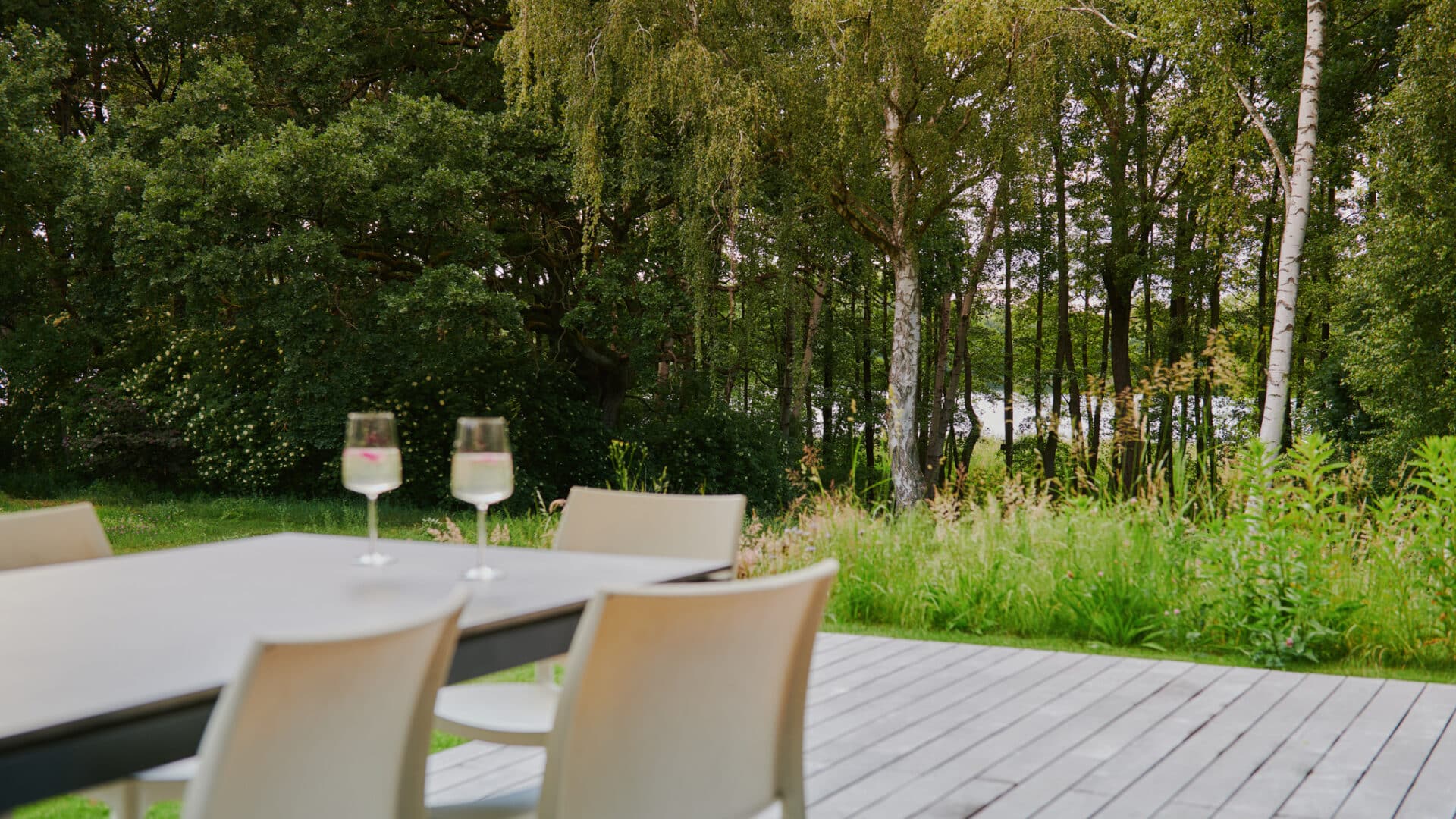 Terrassentisch mit zwei Weingläsern vor Wald