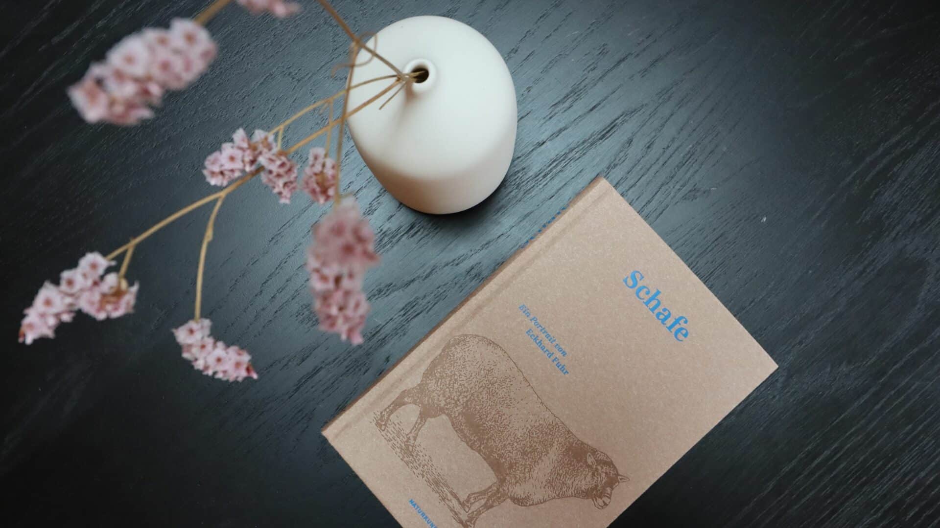 Vase und ein Buch über Schafe auf dem Tisch