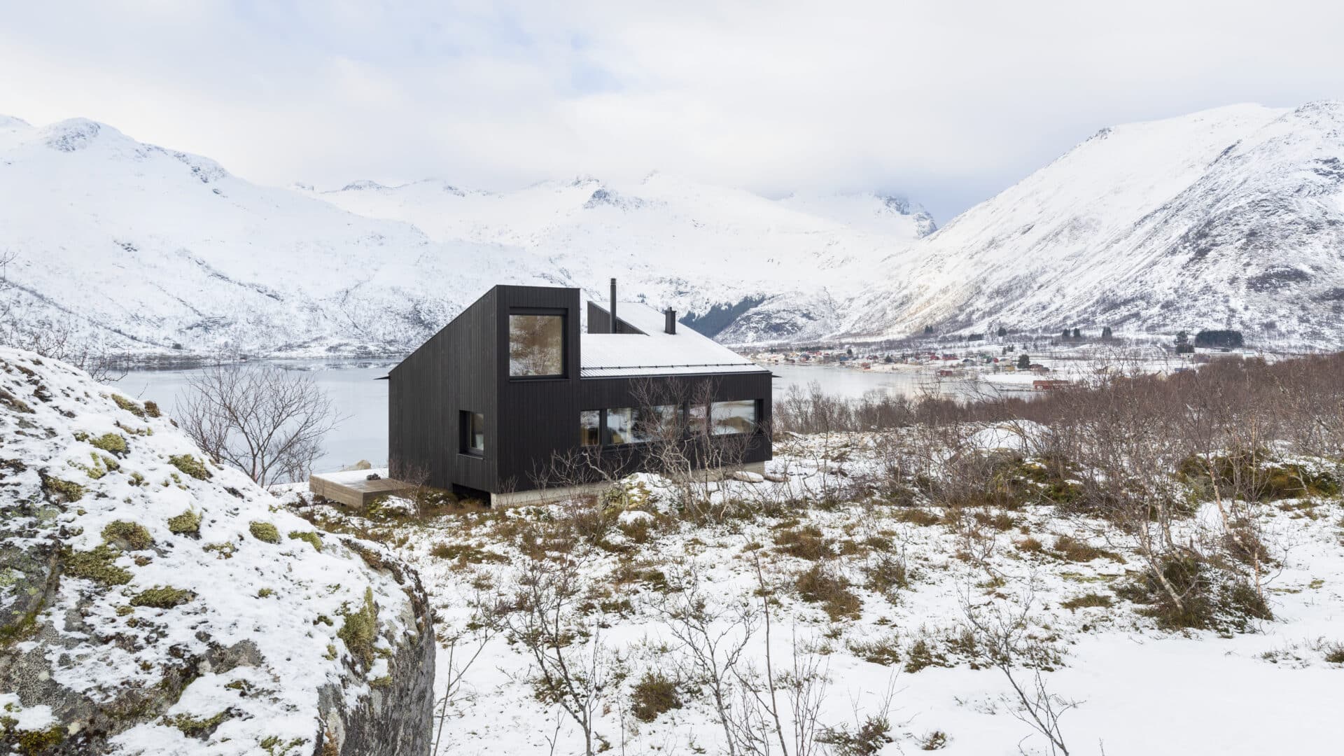 Holzkubus vor schneebedeckten Bergen