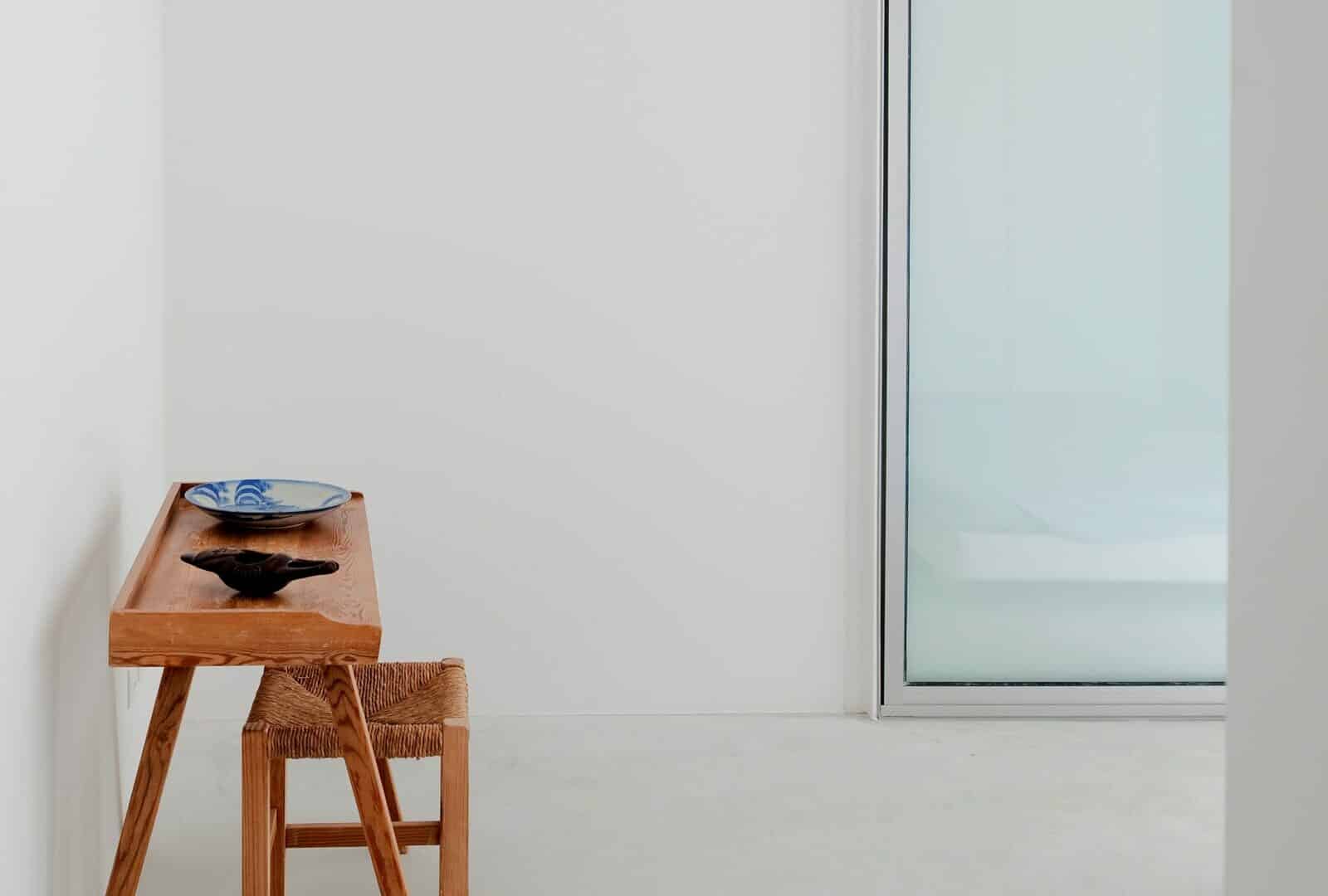 Minimalistischer weißer Raum mit kleinem HolzTisch und -Stuhl