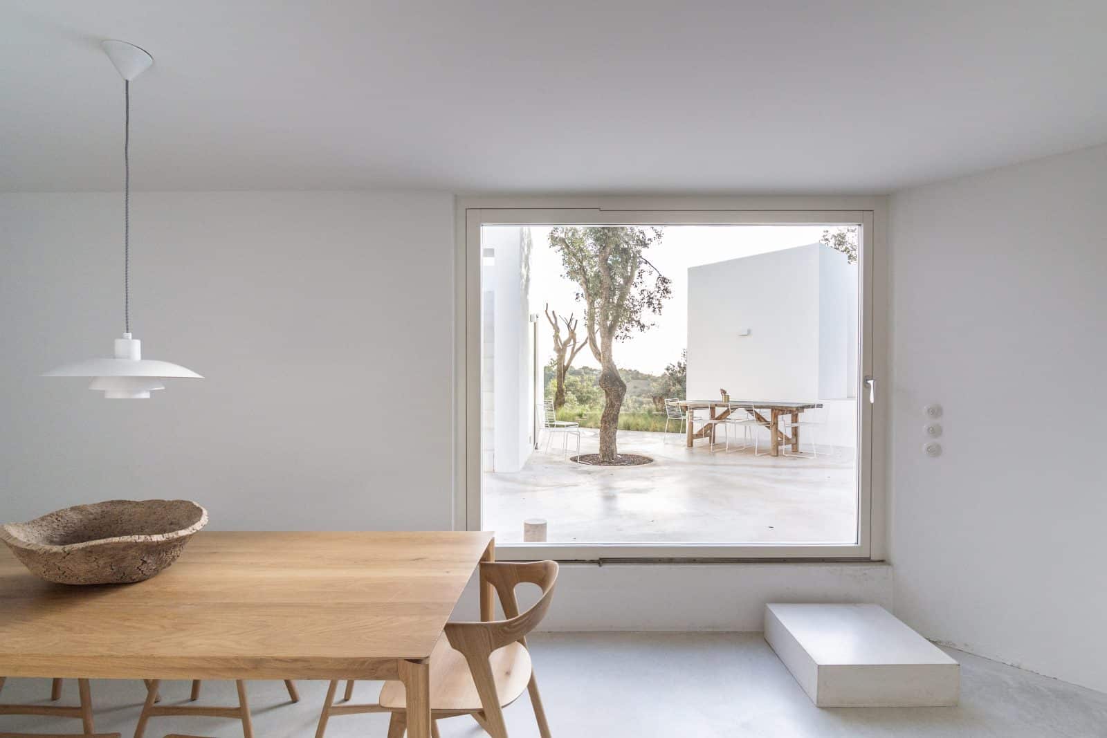 Heller Wohnraum mit Holzesstisch und großem Fenster zur Terrasse