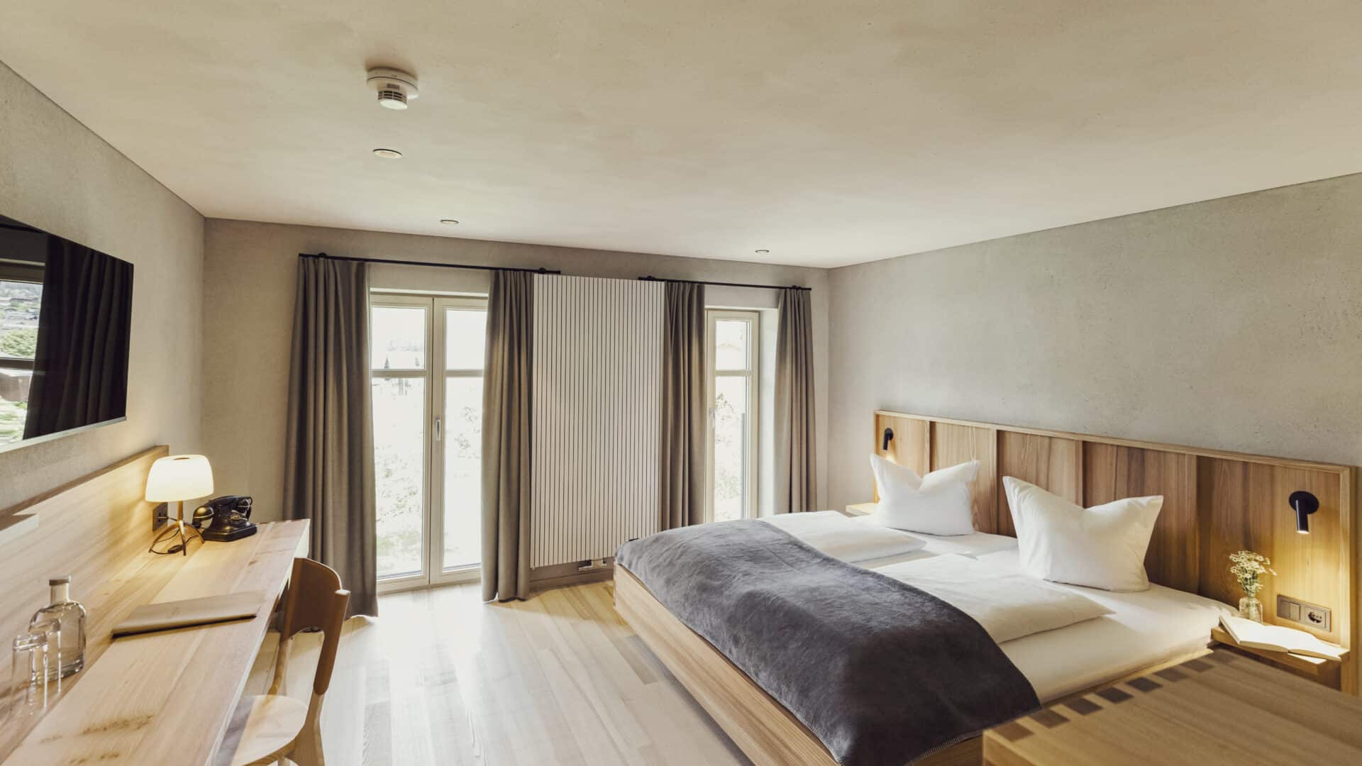 Schlafzimmer mit Doppelbett und zwei bodentiefen Fenstern