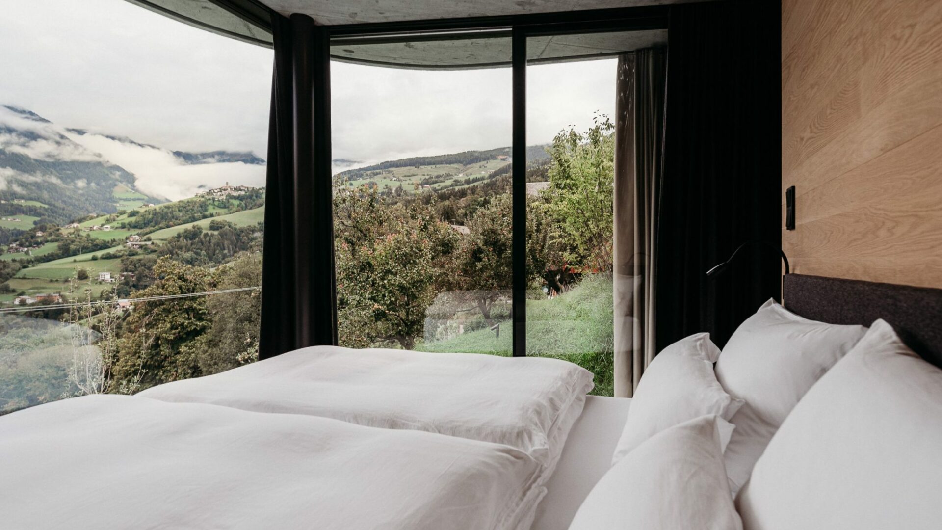 Doppelbett mit Blick aus Panoramafenster auf Berge im Gästehaus Freiform