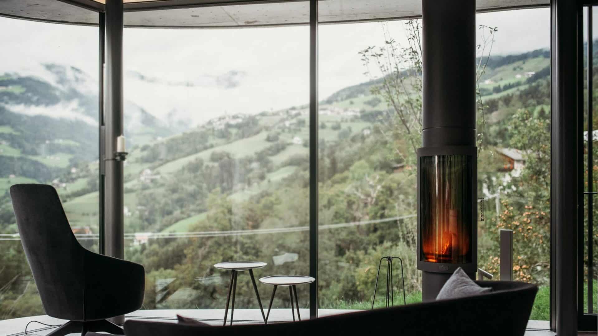 Sessel mit Ausblick aus dem großen Panoramafenster im Wohnzimmer mit Kamin im Gästehaus Freiform