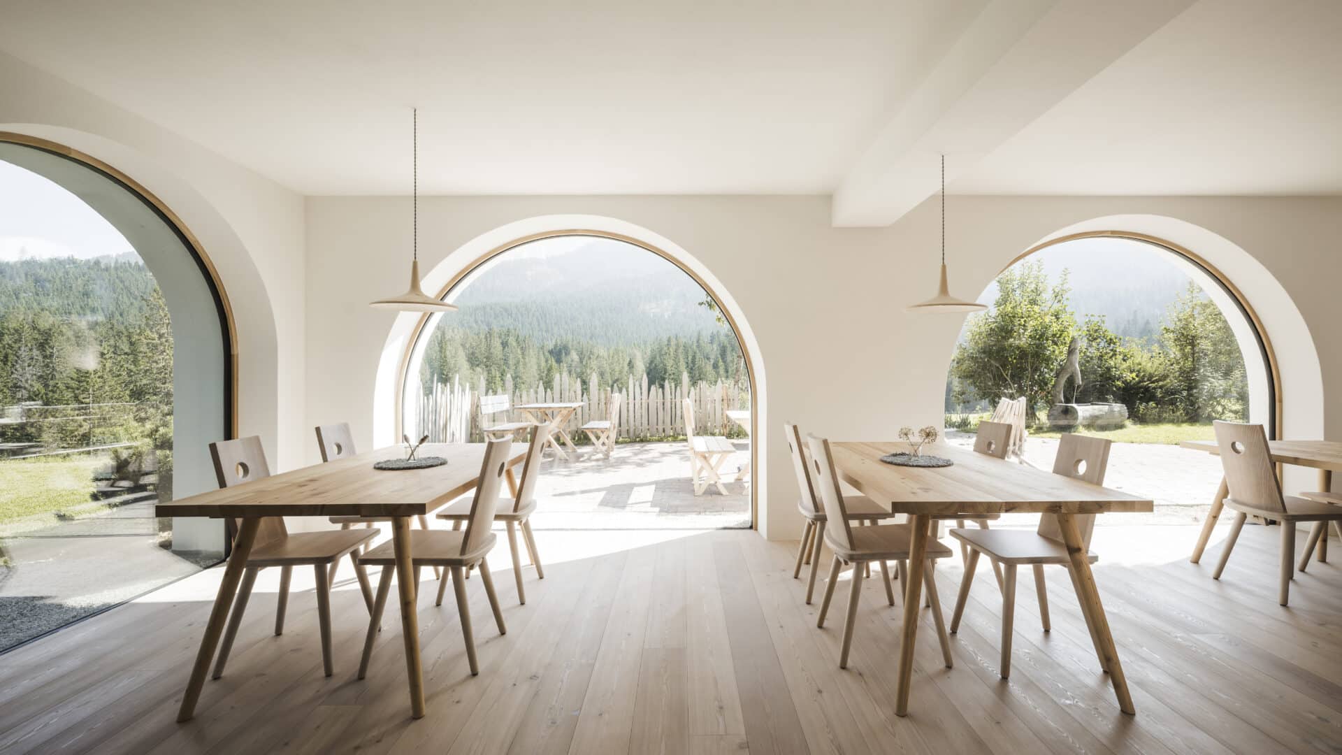 Frühstücksraum mit Holztischen und Rundbogenfenster