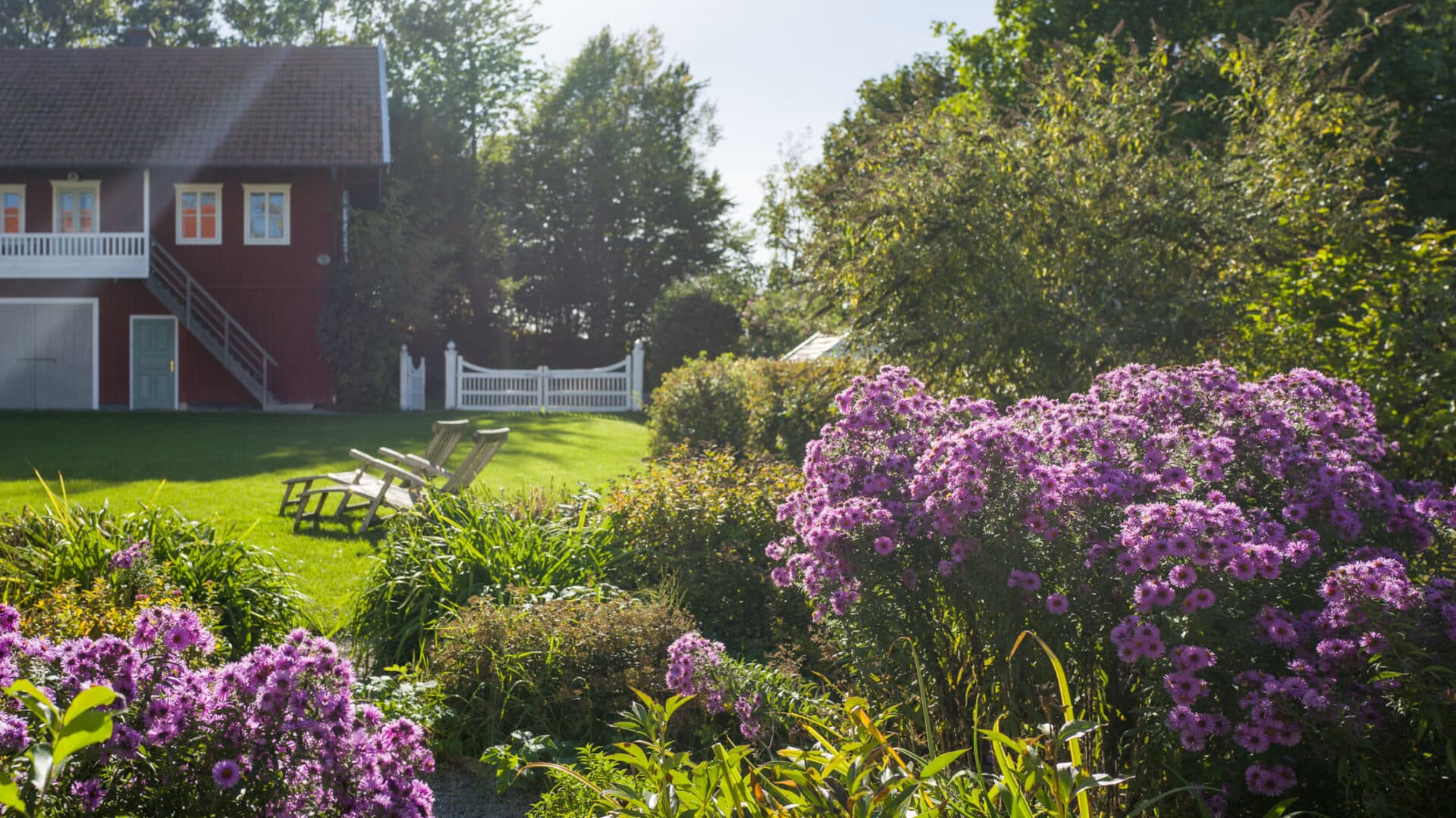 Garten mit Stauden und Sitzplätzen und rotes Haus auf Hof Grillenöd