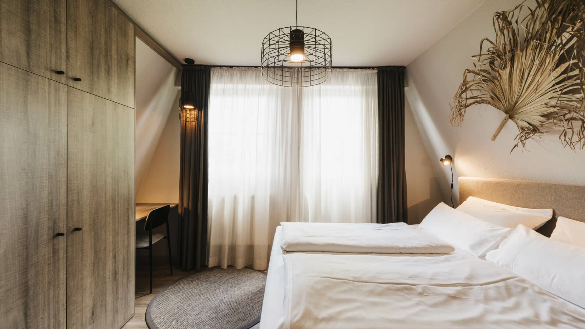 Doppelbett und Palmblatt als Wanddeko und Schrank im Seehotel Gronau