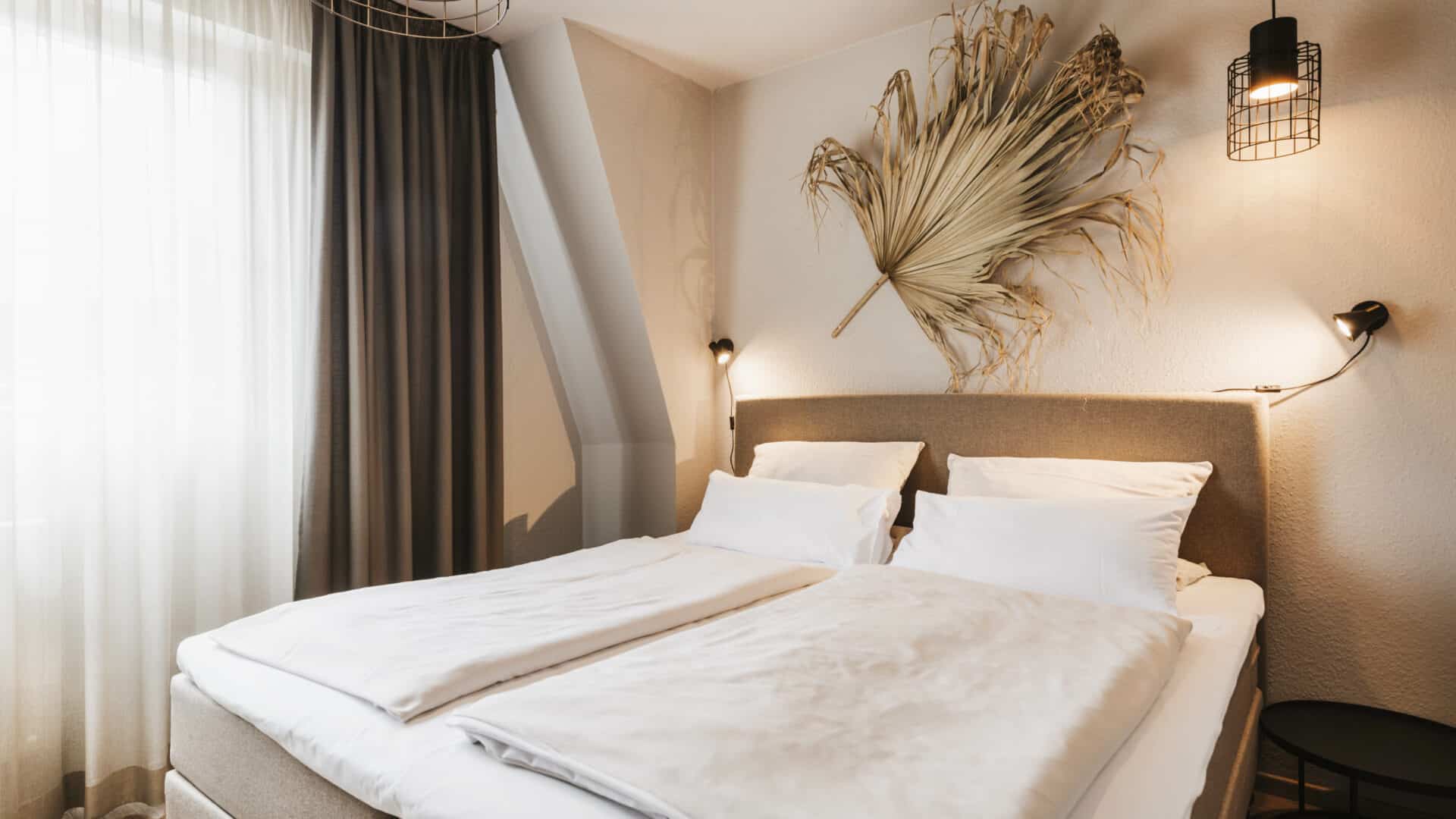 Doppelbett und Palmblatt als Wanddeko im Seehotel Gronau