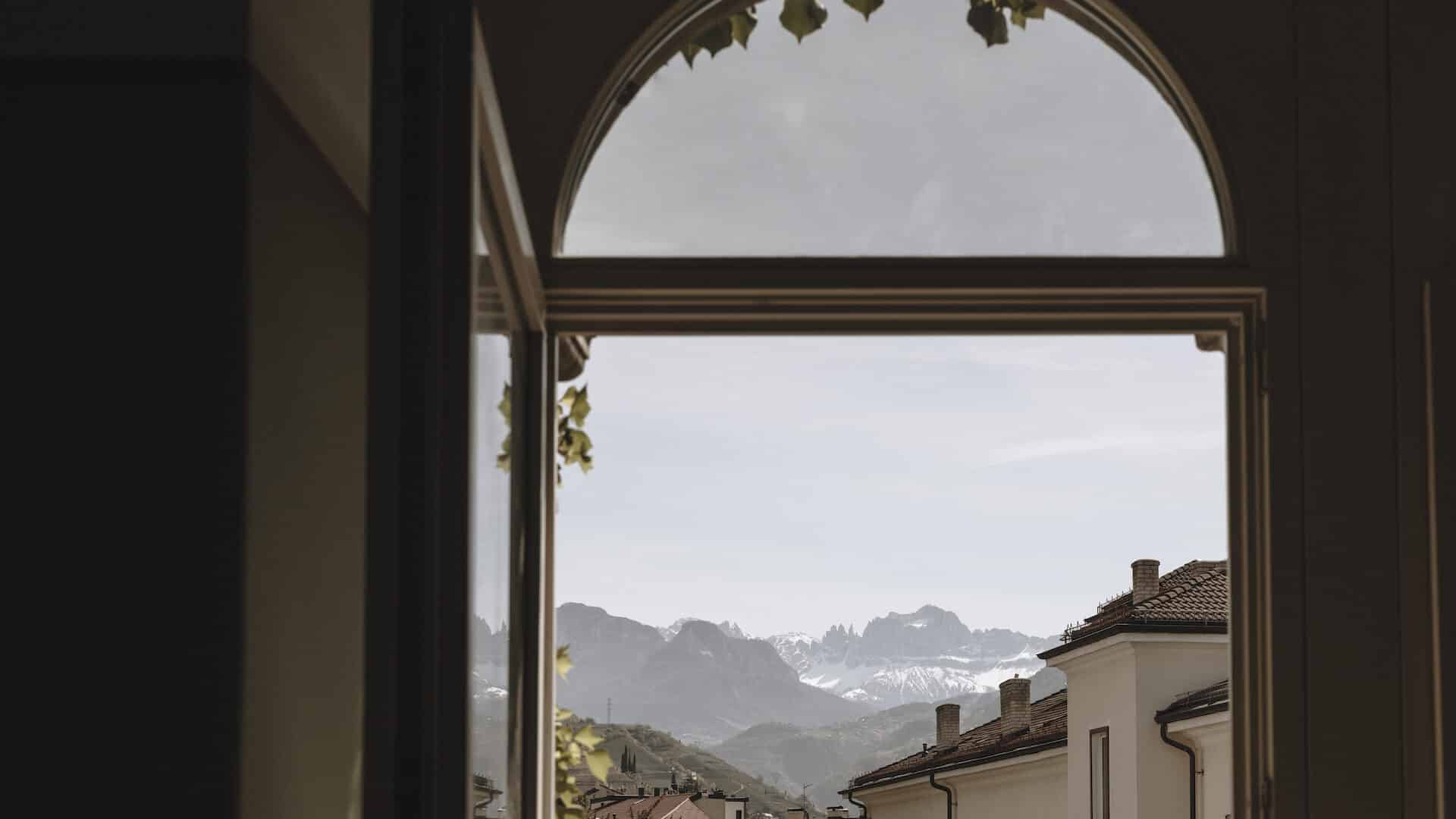 Ausblick durch ein Bogenfenster auf Bozen im Parkhotel Mondsch