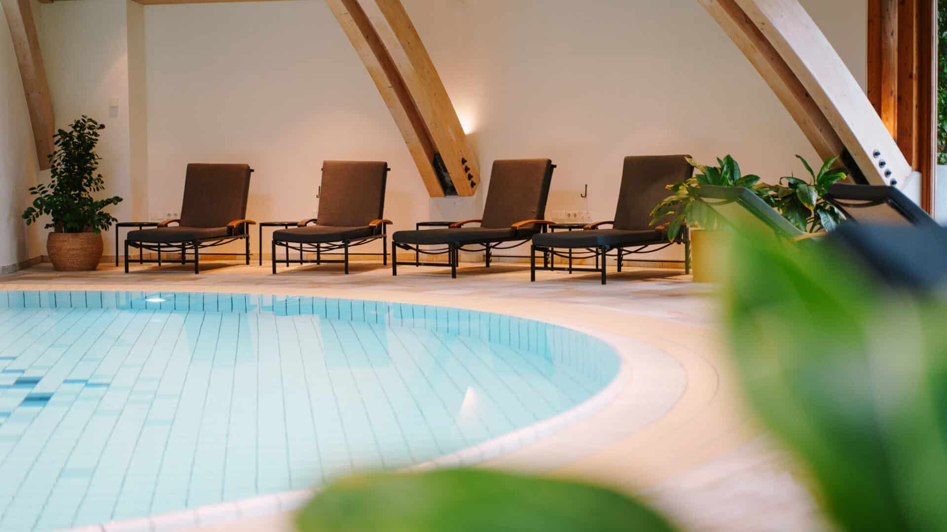 Indoor-Schwimmbad mit Liegen im Daberer Hotel