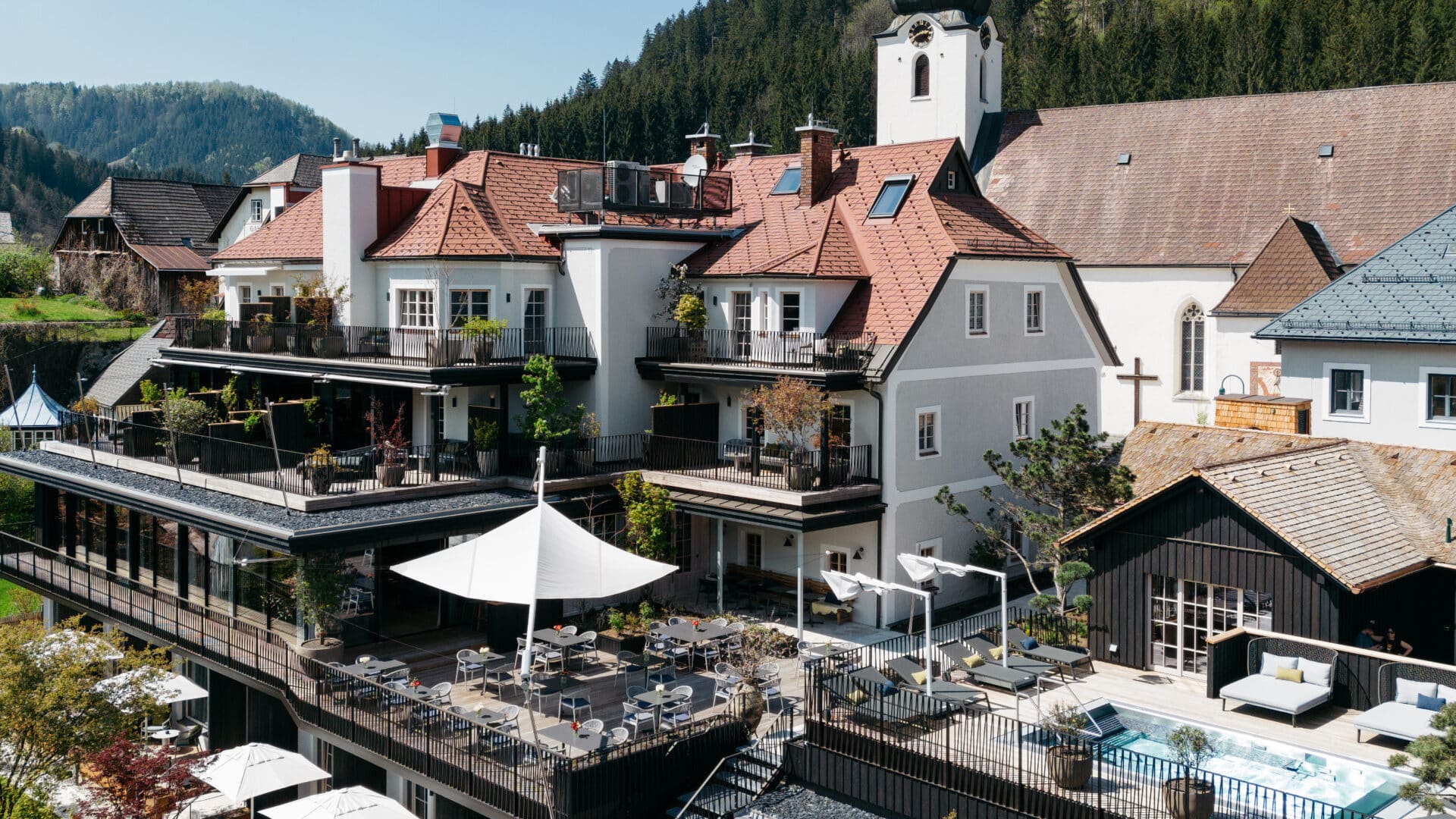 Blick von oben auf die Rückseite des Refugium Lunz mit Restaurantterasse und Pool