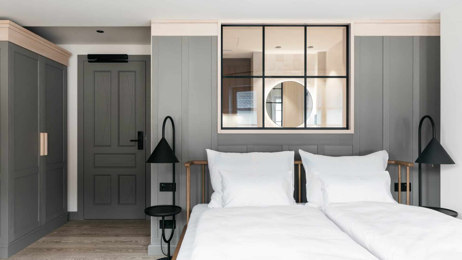 Doppelbett und Badezimmer im Hotelzimmer des Refugium Lunz