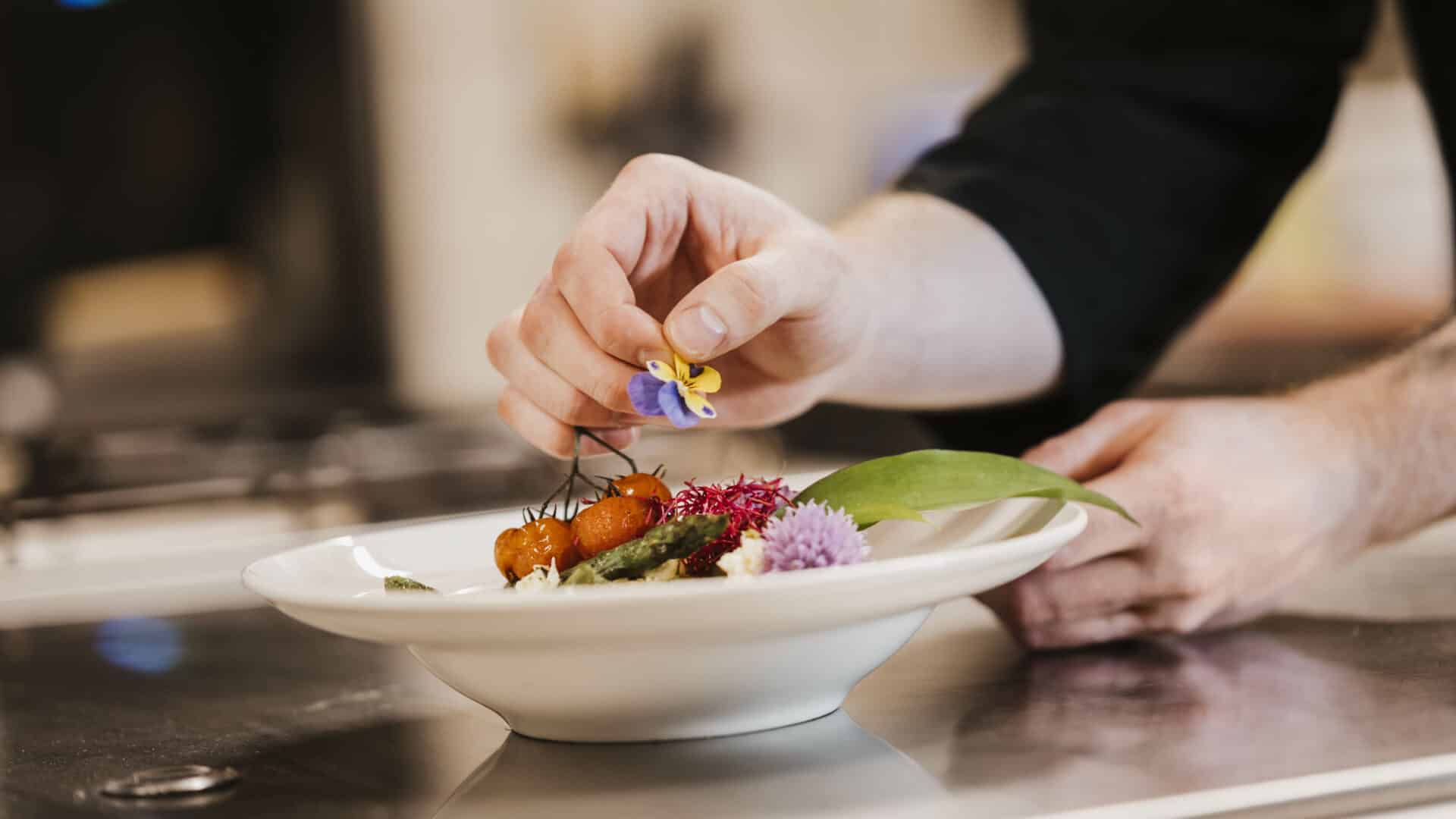 Hand, die eine Schüssel mit einer Blüte dekoriert im Seehotel Gronau