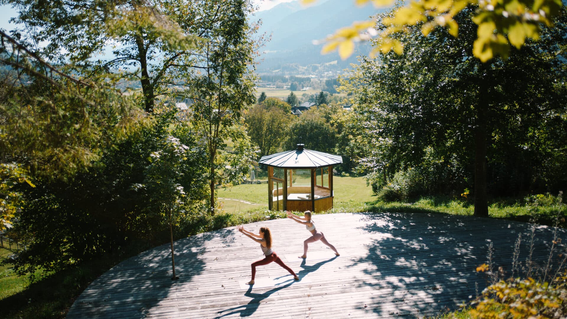 2 Personen die auf einem runden Terrassendeck Yoga machen